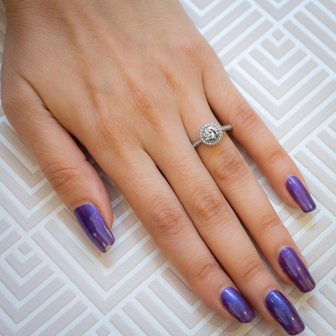 A modern solitaire diamond halo design ring, set with a 0.94 carat round brilliant-cut diamond, in our opinion the colour is H-I and our opinion of the clarity is I2, with surrounding micro pavé set round brilliant-cut diamonds, forming a halo