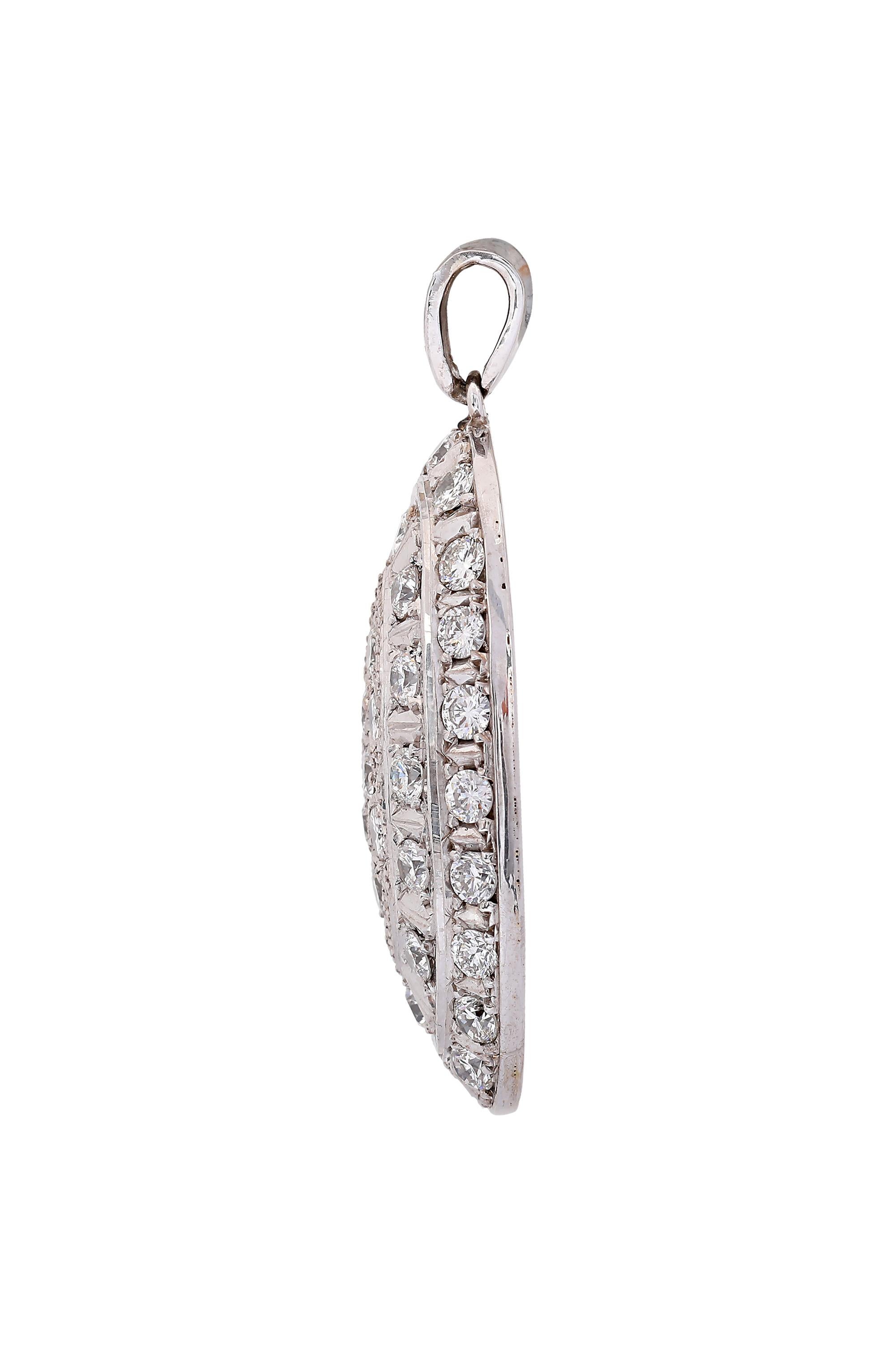 This gently curved oval pendant faces forward with two graduated rows of alternating round brilliant diamonds interspersed by white gold spacers. The center features an oval design of seven round brilliant diamonds in a decorative field of white