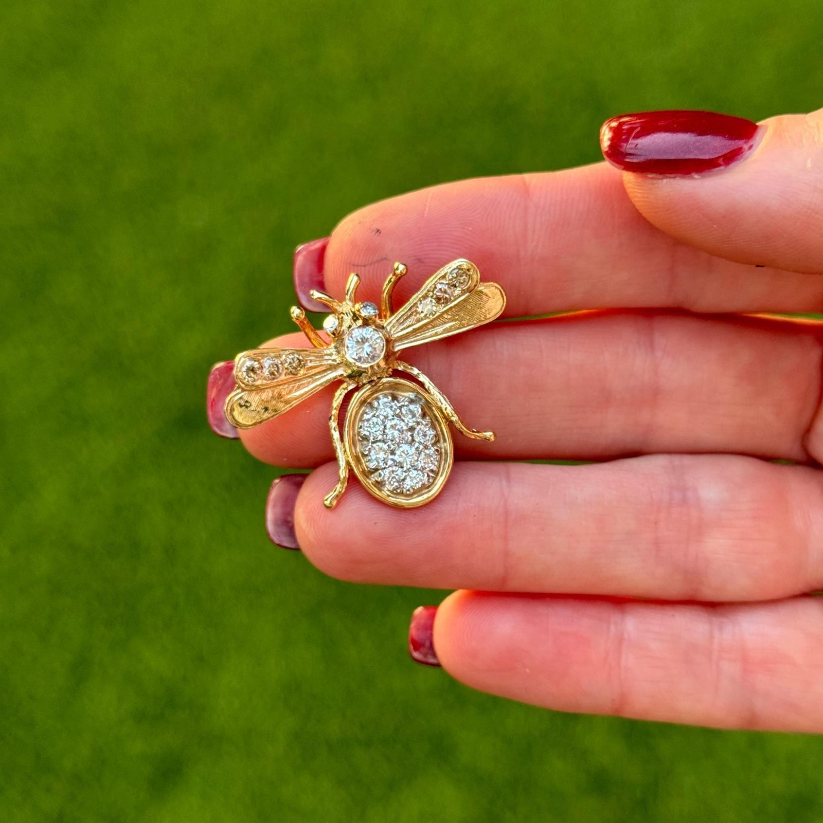 This 14 karat yellow gold diamond bee brooch is a charming and elegant piece, beautifully crafted to capture the delicate details of a bee in flight. It features a center diamond of approximately 0.25 carats, surrounded by 18 round brilliant-cut