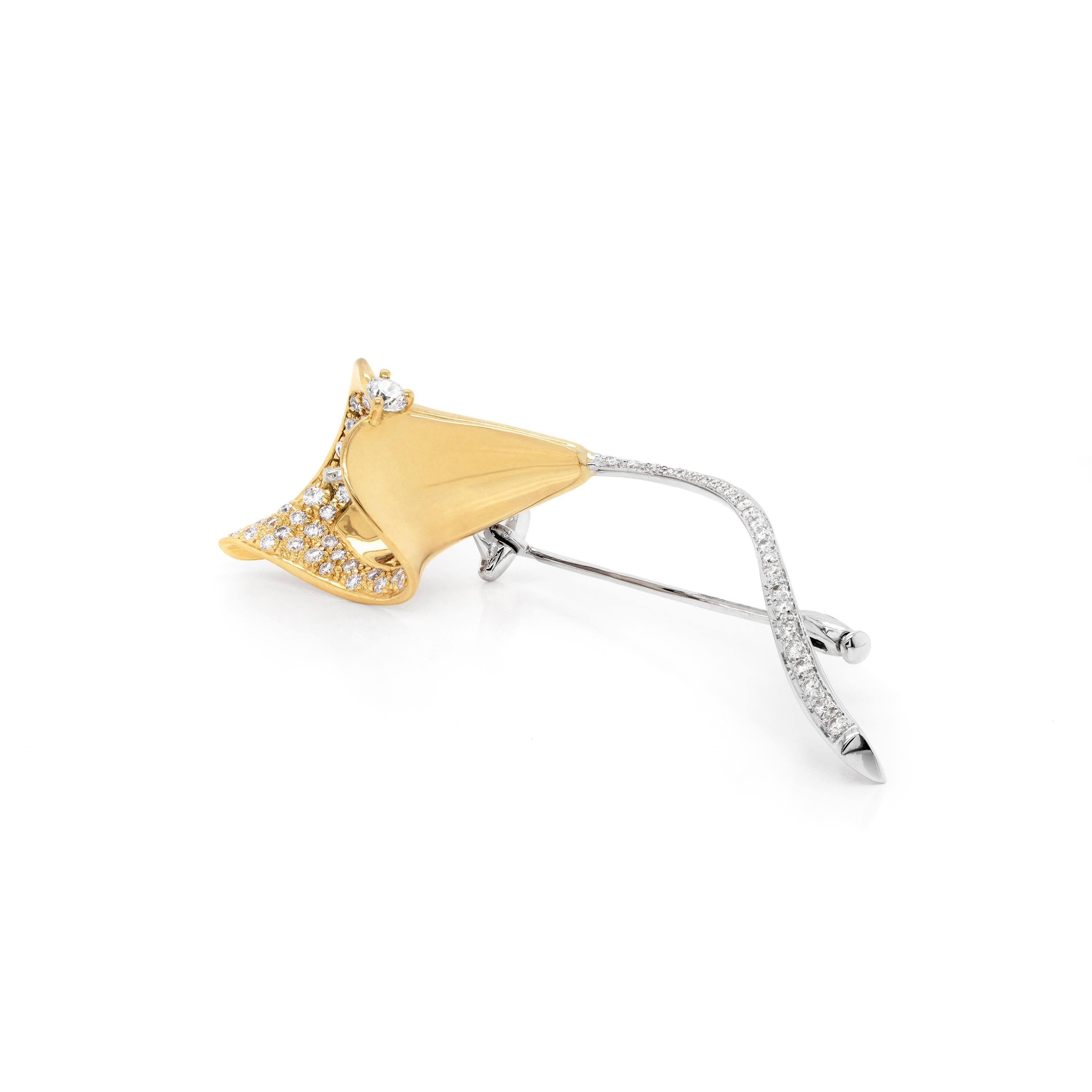 This stunning calla lily flower brooch is made in 18 carat yellow gold with a white gold stem. The brooch is designed as a stylised calla lily, the delicate stem set with a row of round brilliant cut diamonds, and the flower head further jewelled
