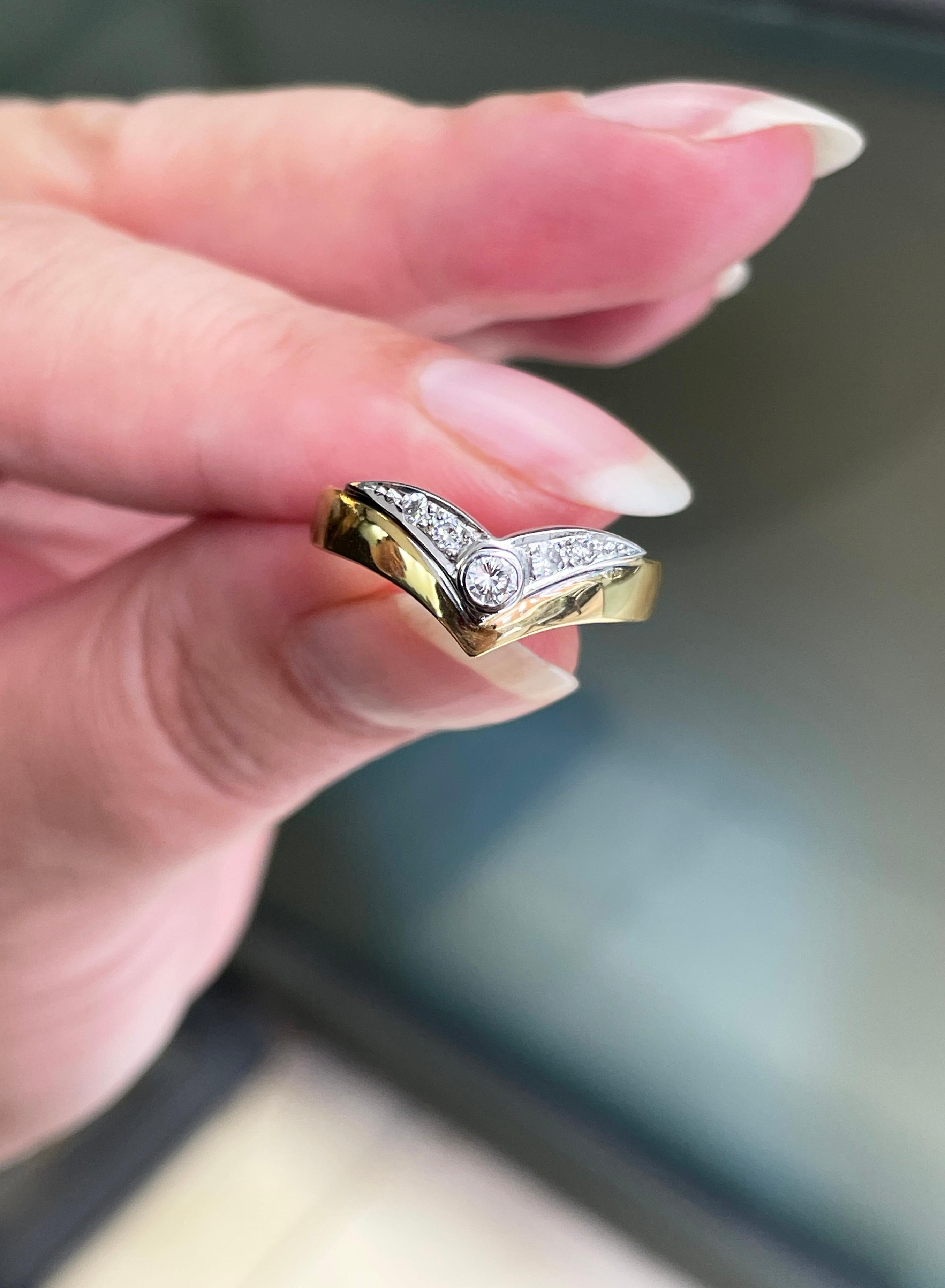 This wonderful two tone wishbone ring is fitted with a rubover set round brilliant cut diamond in the center with two round brilliant cut diamonds on either side weighing a combined 0.20ct all mounted in 18 carat gold. Hallmarked 750.