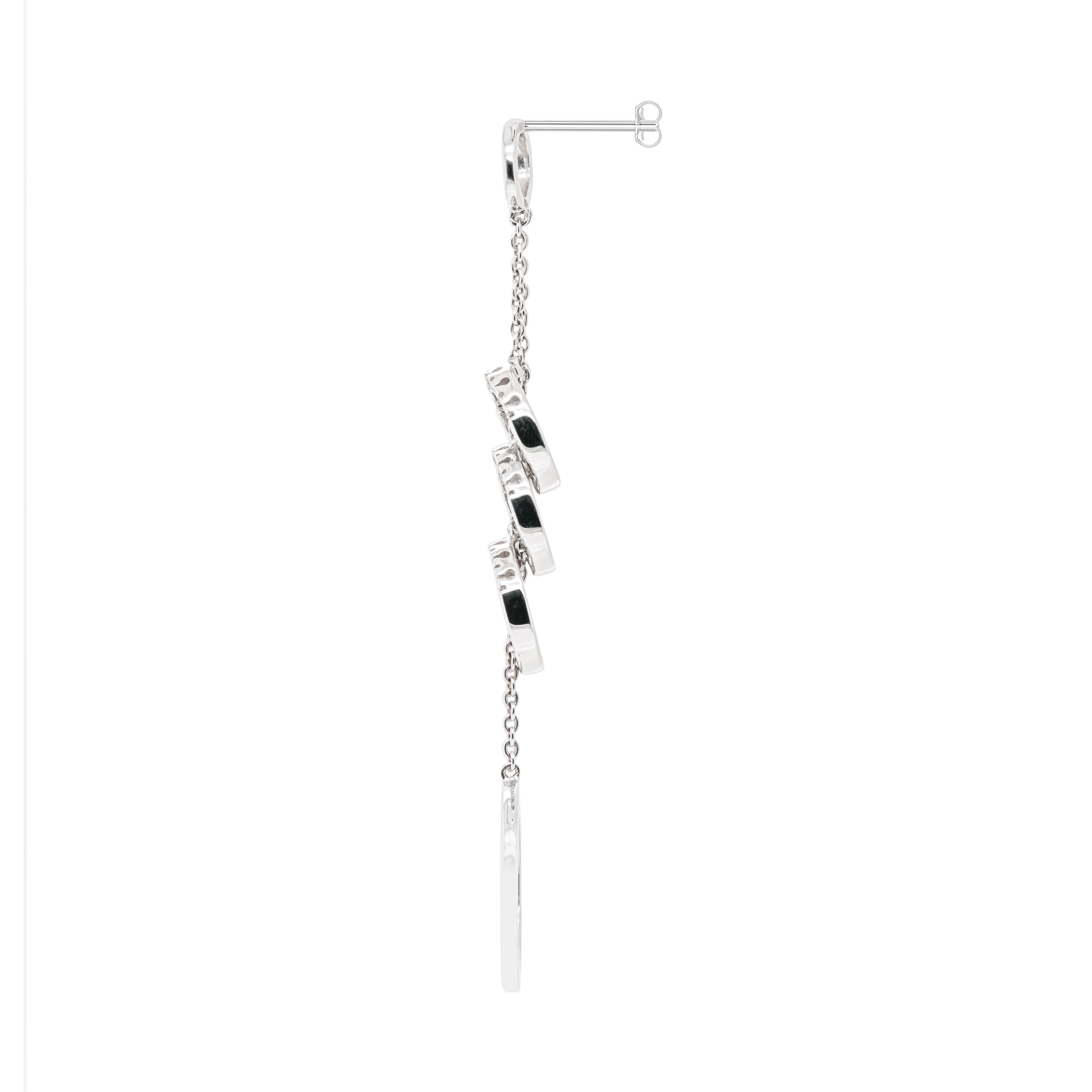 These beautiful 18 carat white gold cascade dangle earrings feature five graduating circles connected by two delicate chains. Slender and dainty, the three middle circles drop sparkle with the shine of six round brilliant cut diamonds inlaid into