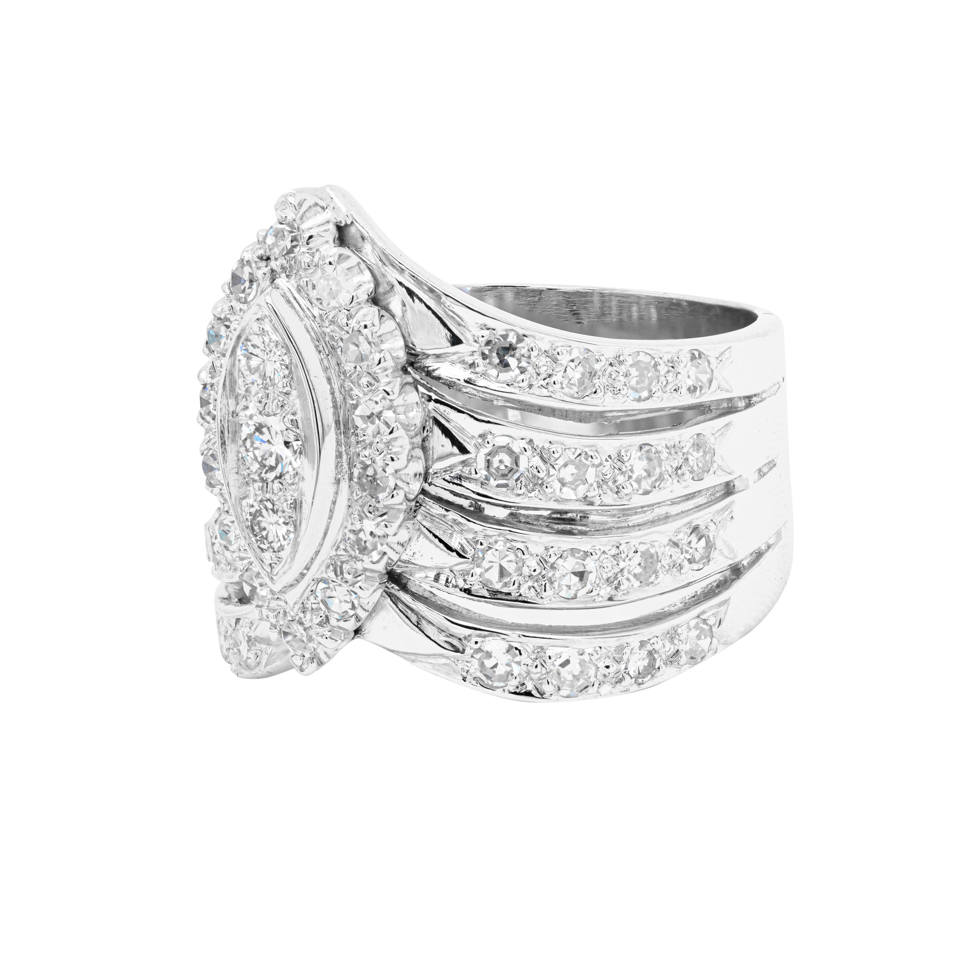 Gorgeous and bold, this 'V' chevron style 18 carat white gold cocktail ring is centred with 3 round brilliant cut diamonds vertically set within a marquise shaped bezel. Highlighting the centre stones there is a beautiful halo of 14 eight cut