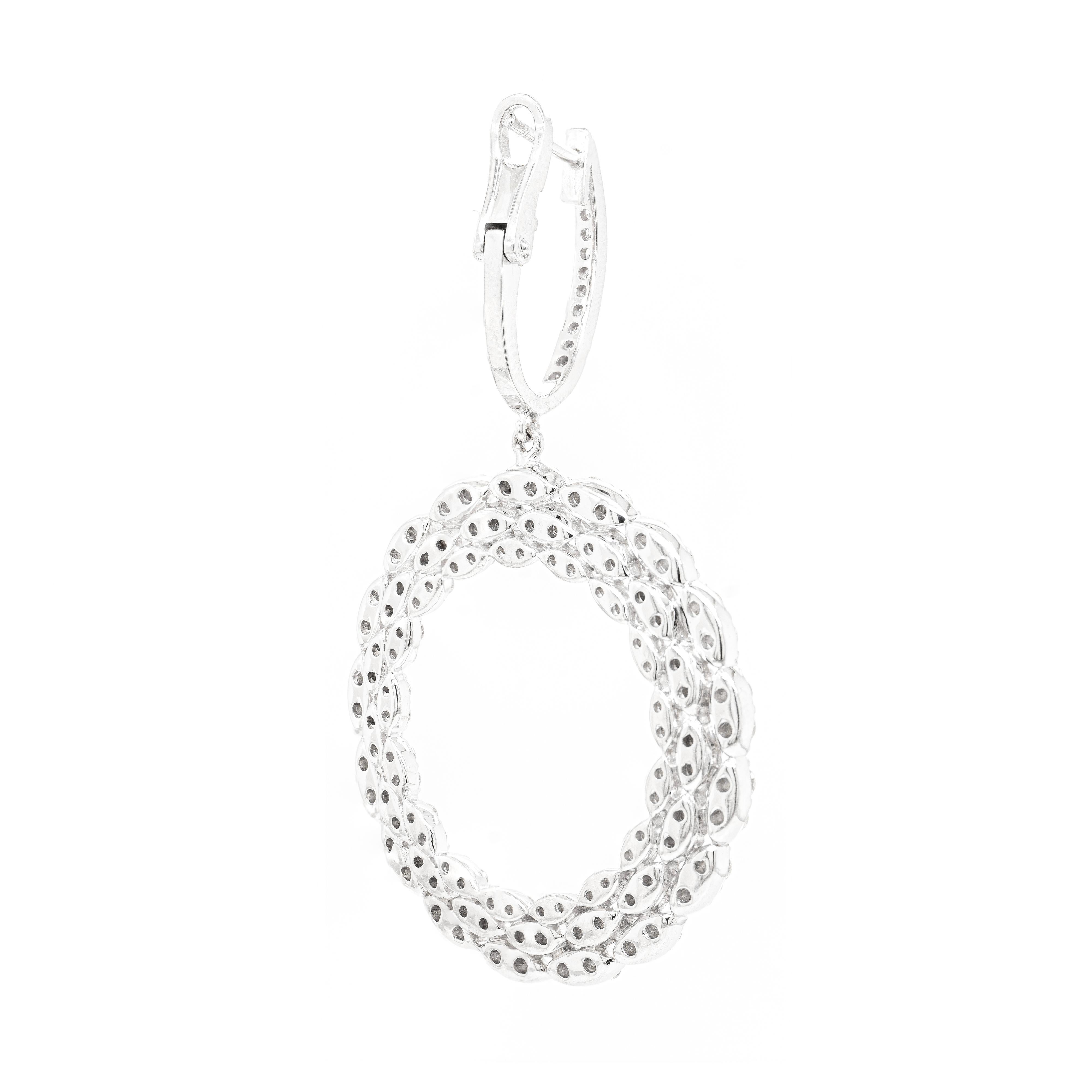 These spectacular dangle earrings feature an open-work front facing circular design, showcasing three rows of delicate marquise shaped 18 carat white gold mounts, each inlaid with two round brilliant cut diamonds. The large circle suspends from an