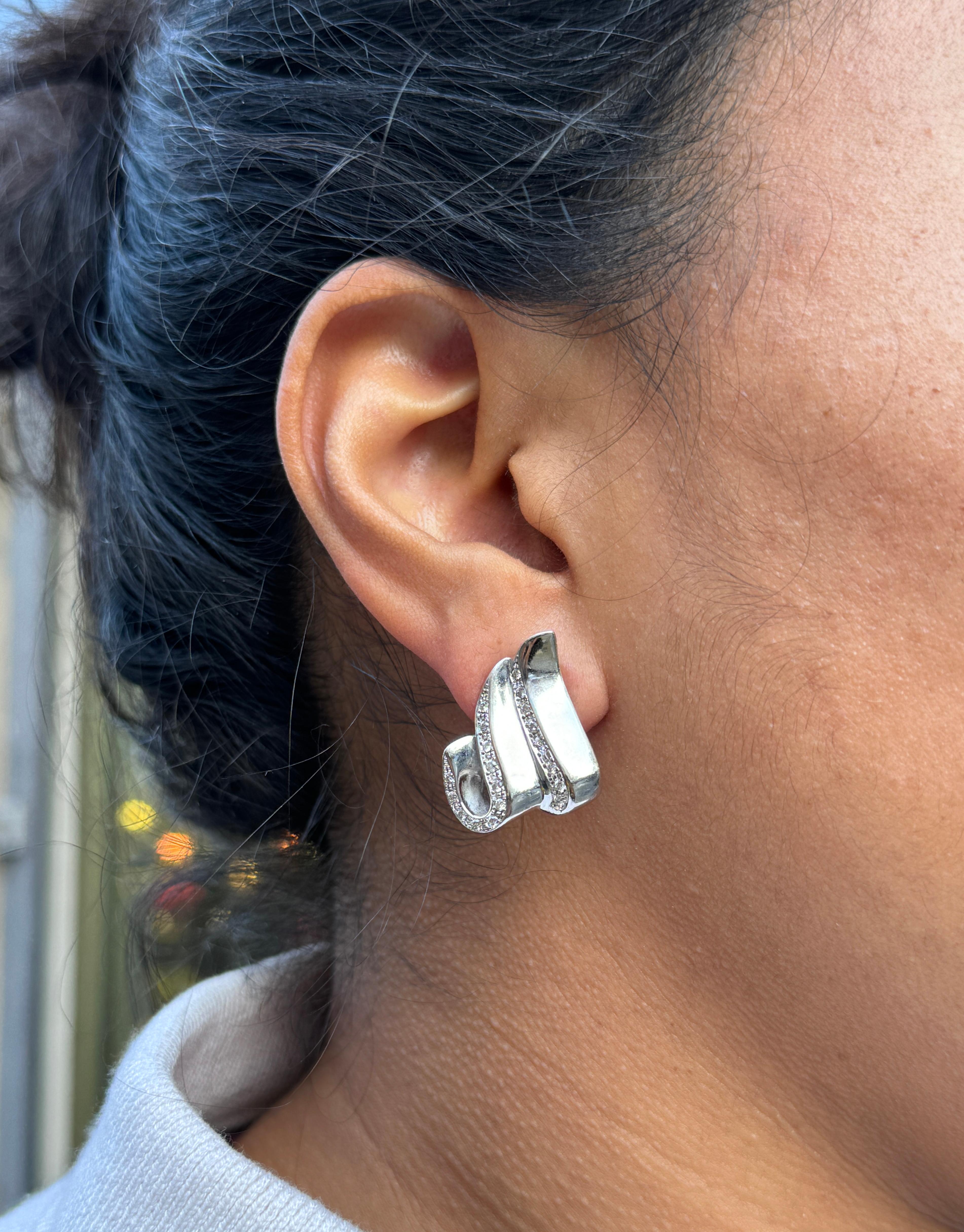 Crafted from high quality 18 carat white gold, these lever-back earrings are simply fantastic!

The pair showcases an intricate design consisting of flowing, ribbon-like curves, beautifully adorned with delicate rows of grain set round brilliant cut
