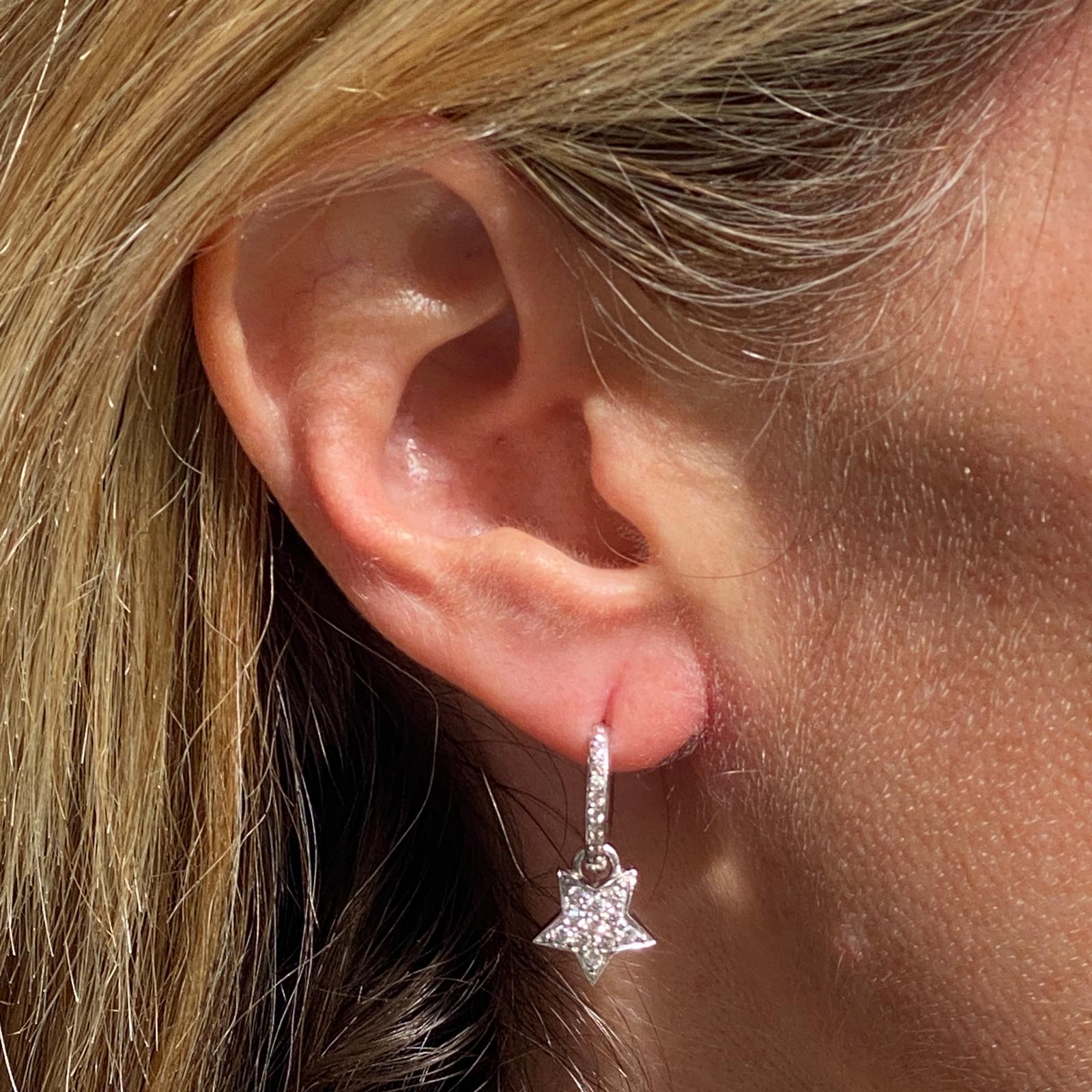 Diamond hoop star dangle earrings fashioned in 18 karat white gold. The hoops and stars feature 38 round brilliant cut diamonds weighing .46 carat total weight and graded H-I color and SI clarity. The hoops and star drops measure .90 inches in