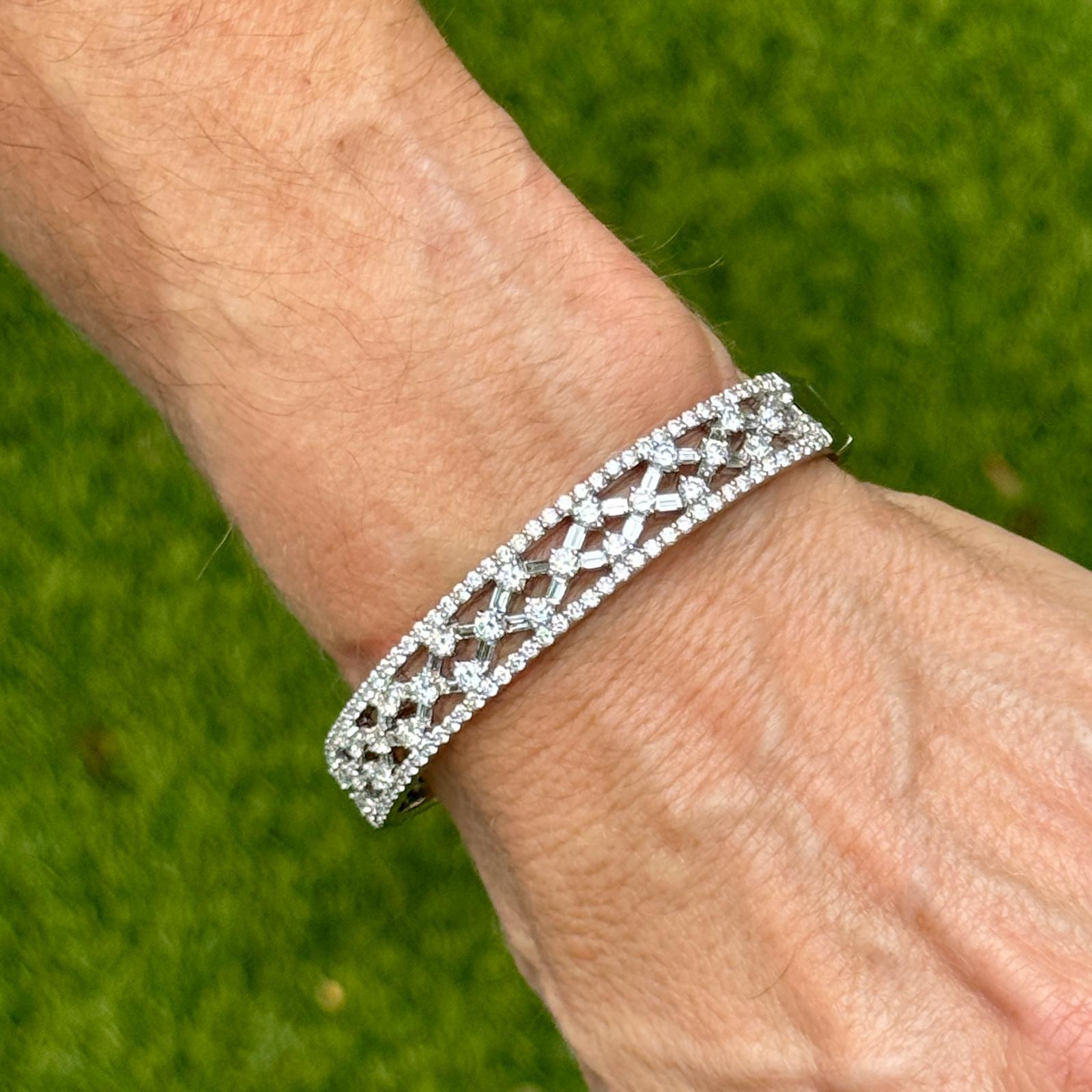 Elegant and intricately detailed, this 18 karat white gold oval bangle showcases a stunning open lattice design adorned with shimmering diamonds across the top. A total of 138 diamonds, combining 26 round brilliant cuts (~2.00 ctw), 80 round