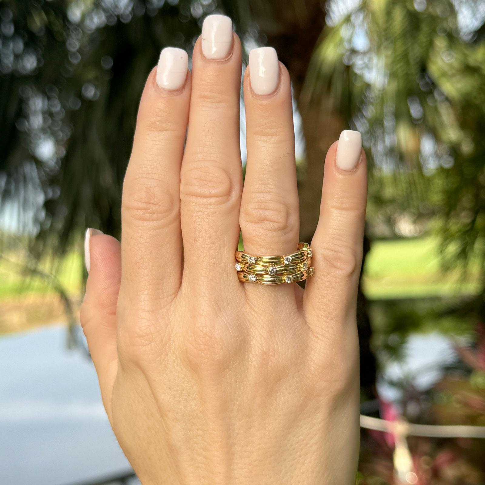 This elegant 18 karat yellow gold band ring features a bamboo-inspired design, with three textured rows that beautifully emulate the organic look of bamboo. Scattered across the band are 10 round brilliant cut diamonds totaling 0.50 carats, with G-H
