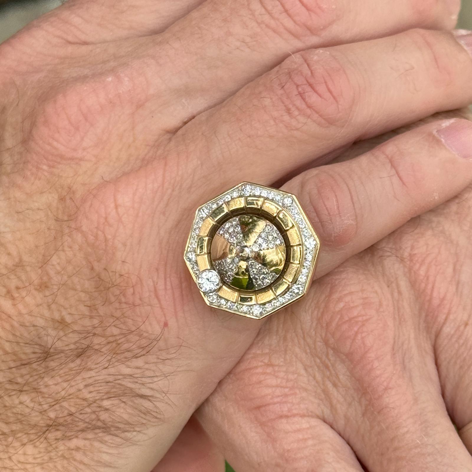 Gents diamond roulette wheel spinner ring handcrafted in 18 karat yellow gold. The ring features 51 round brilliant cut diamonds weighing approximately .79 carat total weight and graded G-H color and VS2-SI1 clarity. The ring measures 25 x 25mm on