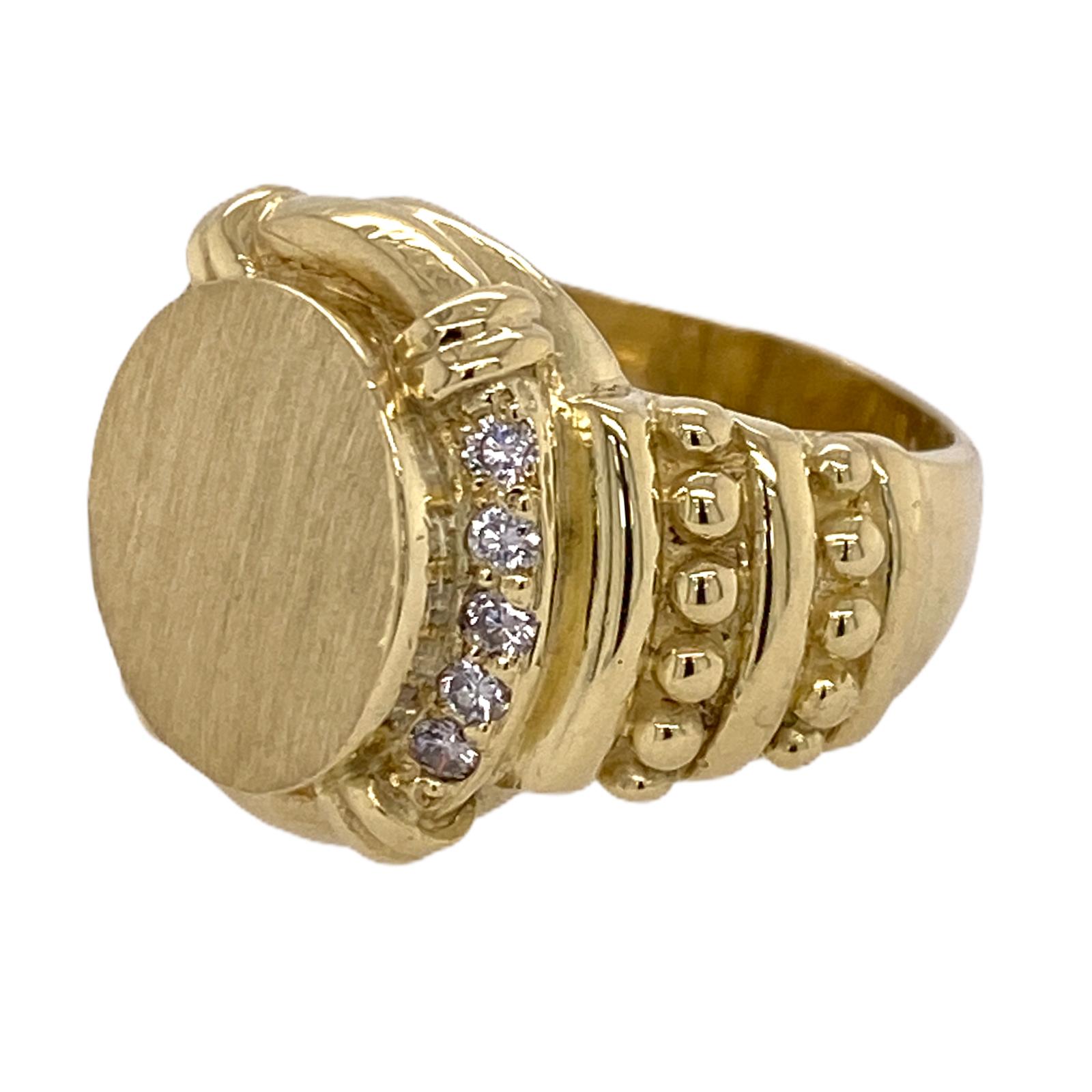 Diamond signet ring fashioned in 18 karat yellow gold. The oval flat top ring is ready for engraving and features round brilliant cut diamond accents weighing .15 carat total weight. The ring measure 11.5 x 12.5mm on top (for engraving), 17mm in