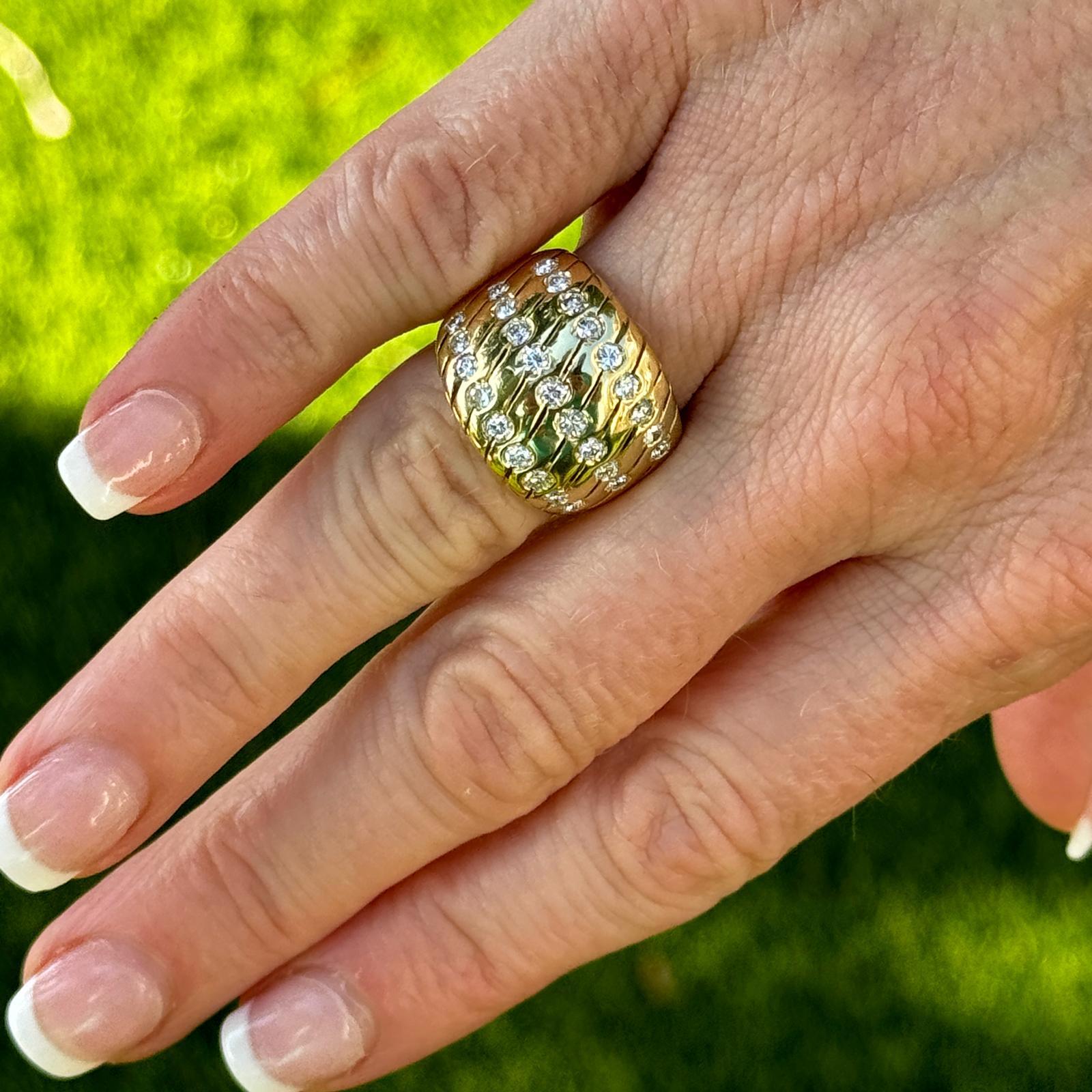 Diamond dome band ring crafted in 18 karat yellow gold. The band features 27 round brilliant cut diamonds weighing approximately 1.00 carat total weight and graded H-I color and SI clarity. The ring measures 16mm in width tapering down to 5mm and is