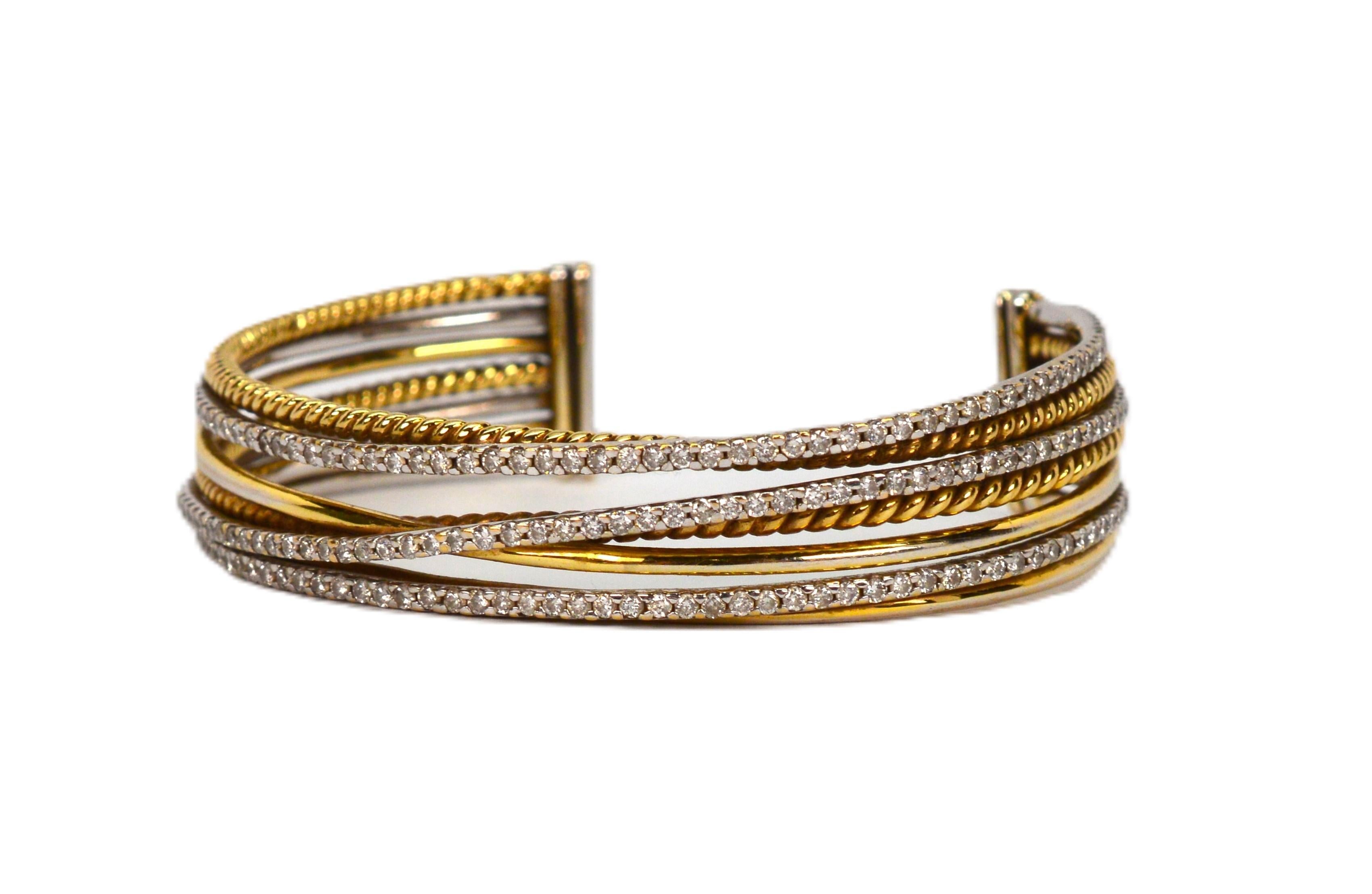 Textures attract on this contemporary style 2-1/2 inch cuff bracelet in mixed media. Separate but intertwining slender bands of both smoothly polished and twisted patterned 18 karat yellow gold mingle with diamond covered white gold bands to create