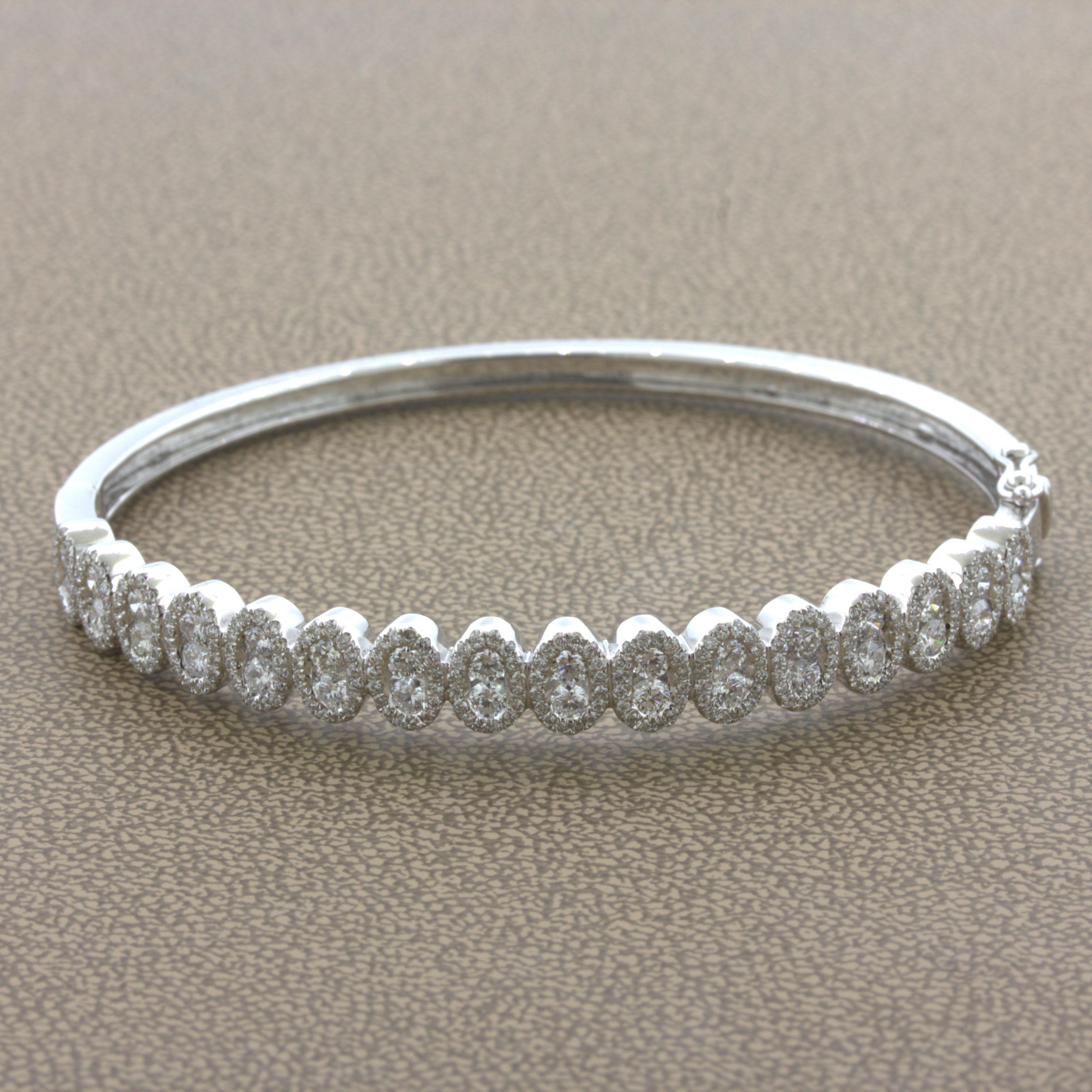 A modern and stylish bangle bracelet featuring 1.36 carats of bright white VS quality diamonds. They are set in vertical pairs with halos of smaller round brilliant-cut diamonds set around them. Made in 18k white gold and ready to be worn.

Outer