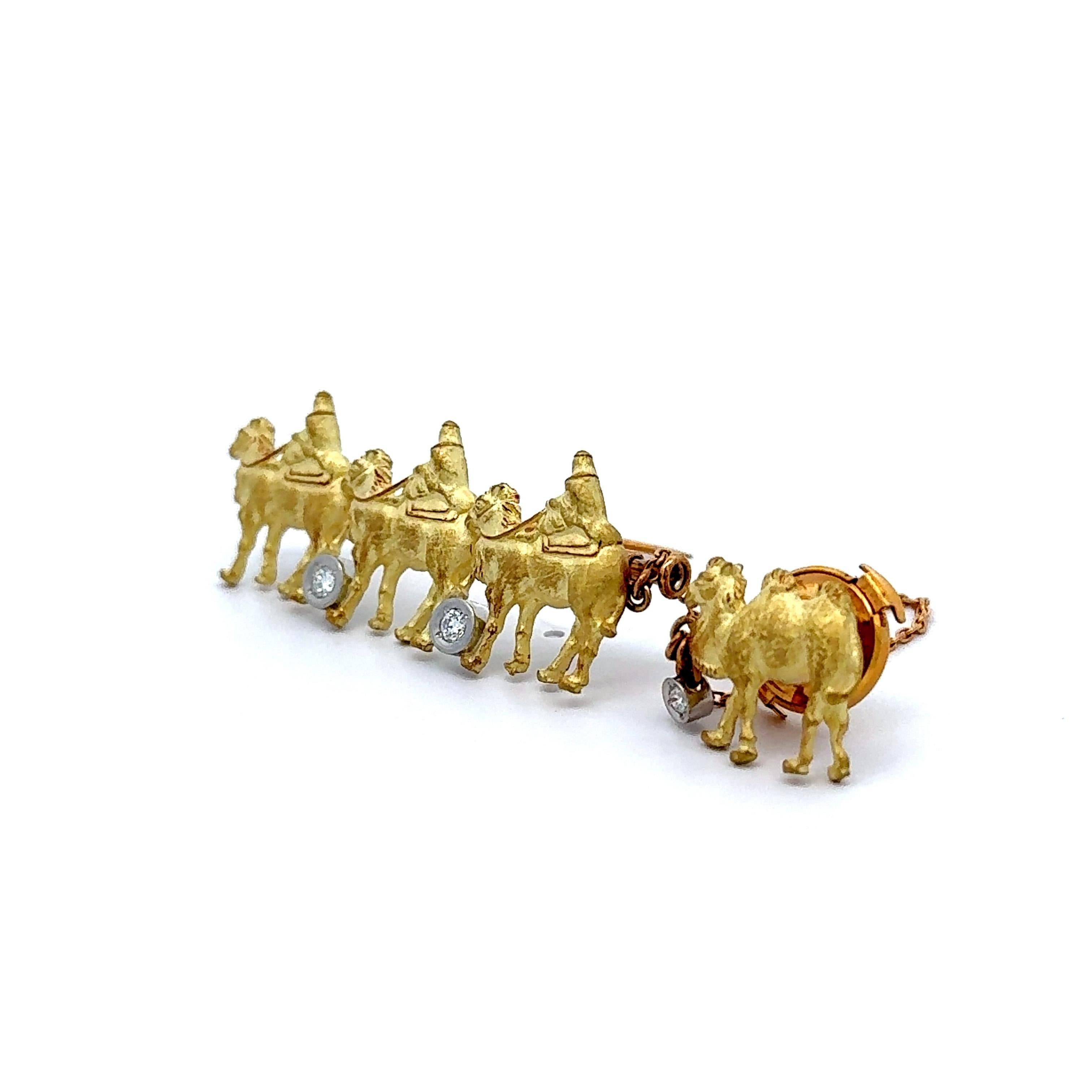 A fanciful brooch or tie-pin featuring a caravan of camels crafted in 18k yellow gold. Each camel is adorned with a round brilliant-cut white diamond, adding a touch of sparkle. The intricate detailing of the camels and riders enhances the design's