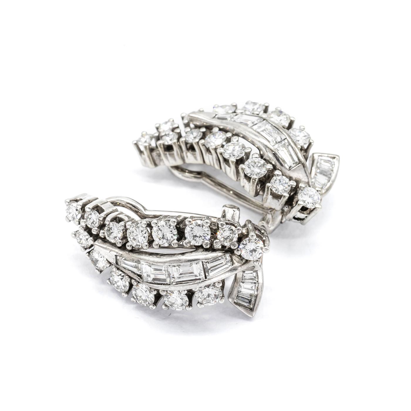 A pair of vintage diamond earrings, in the shape of a stylised leaf, with a ribbon of channel set baguette-cut diamonds, surrounded by claw set round brilliant-cut diamonds, with an estimated total weight of 3.00ct, mounted in white gold, stamped