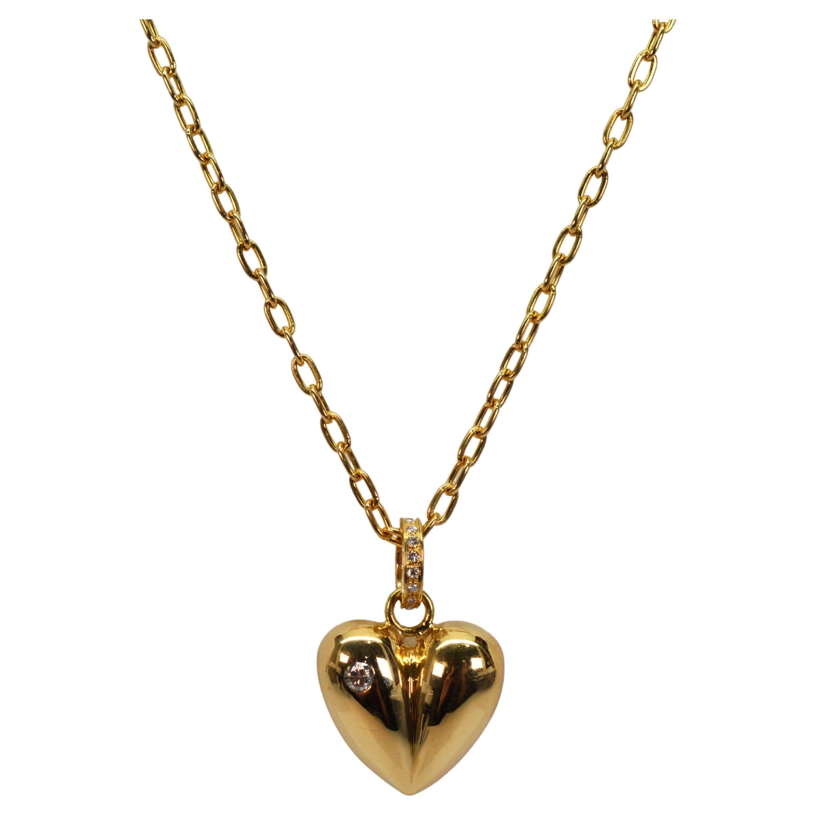With a full heart, plump in 18 karat yellow gold, this beautifully appointed pendant has two bezel set diamond accents, one each .05 carat diamonds on each side of this lovely heart charm.
Elegantly suspend by a diamond encrusted gold bail covered
