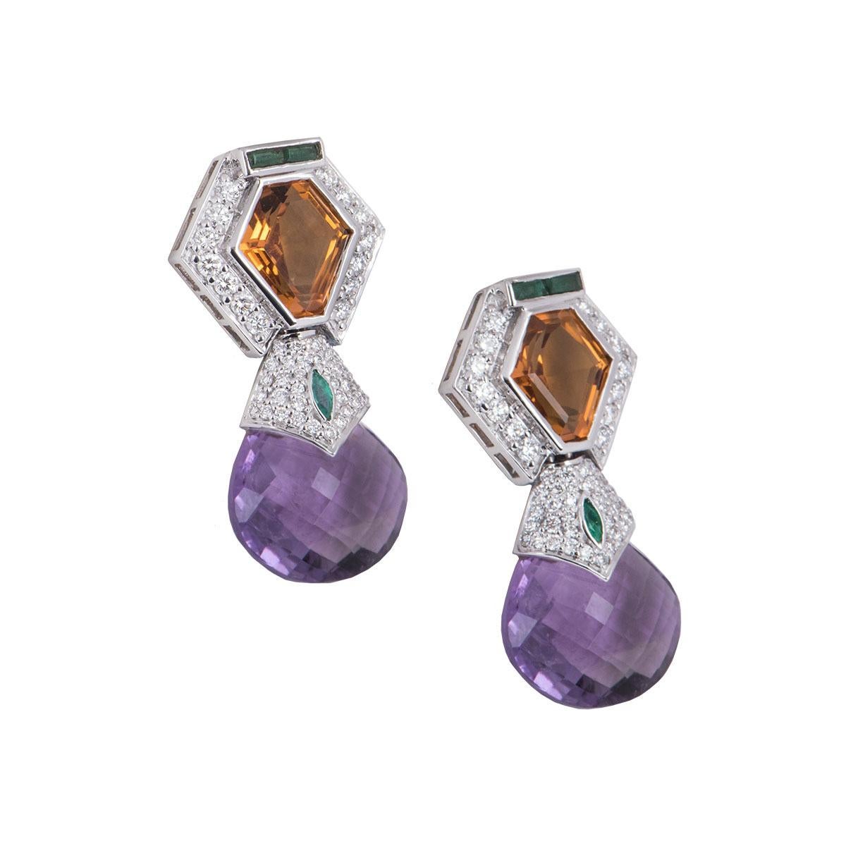 An 18k white gold pair of diamond, amethyst and citrine earrings. The earrings feature a citrine stone set in the centre with round brilliant cut diamonds surrounding it with a tear drop shaped amethyst suspended underneath it moving freely. The