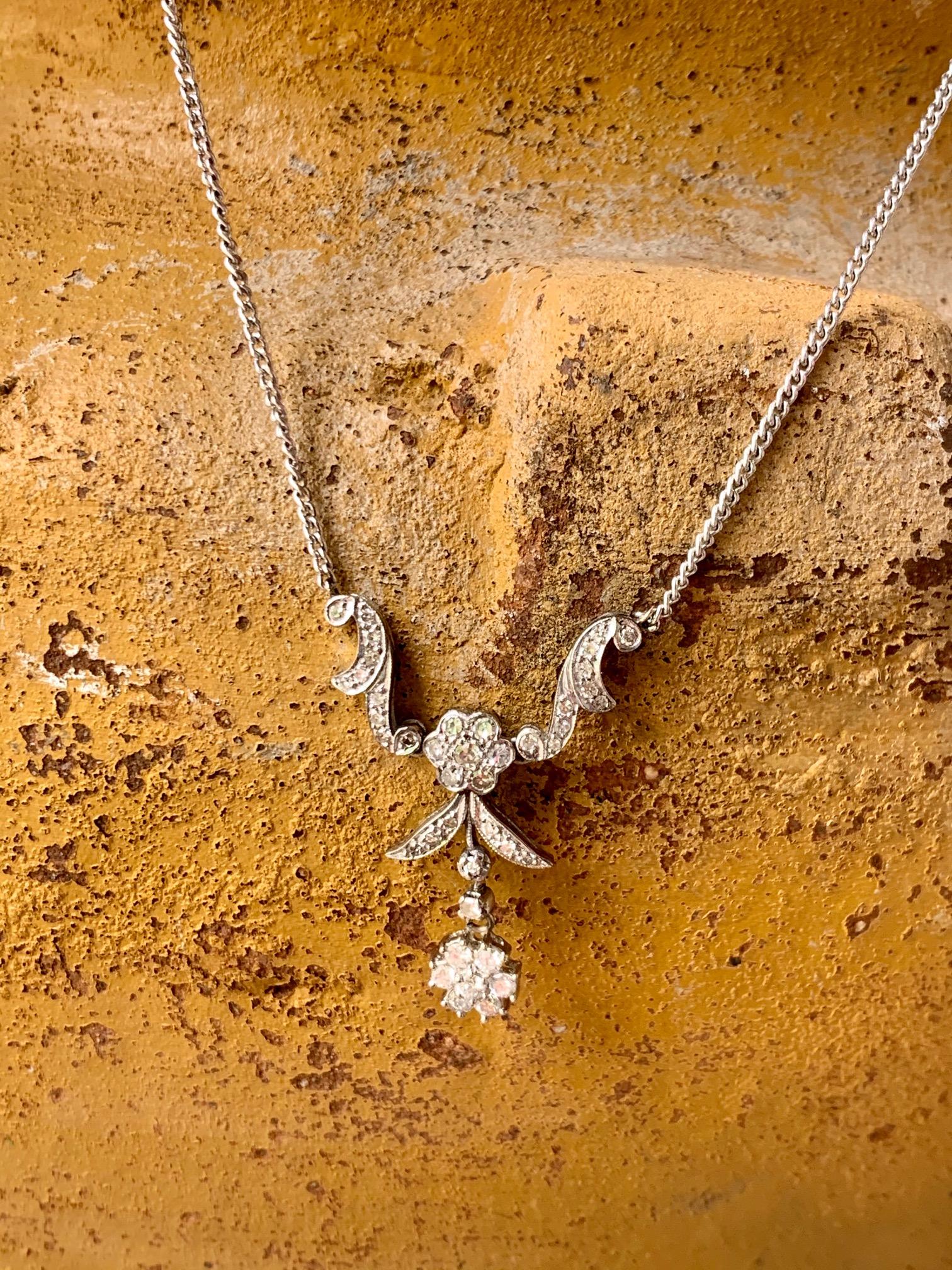 This is a uniquely-shaped pendant with diamonds set into 14k white gold.   There are single and full cut diamonds featured in a scroll design reaching downwards to the center flower within the pendant.
cwt:  .80
Quality:  VS to SI
Color: H-J
The