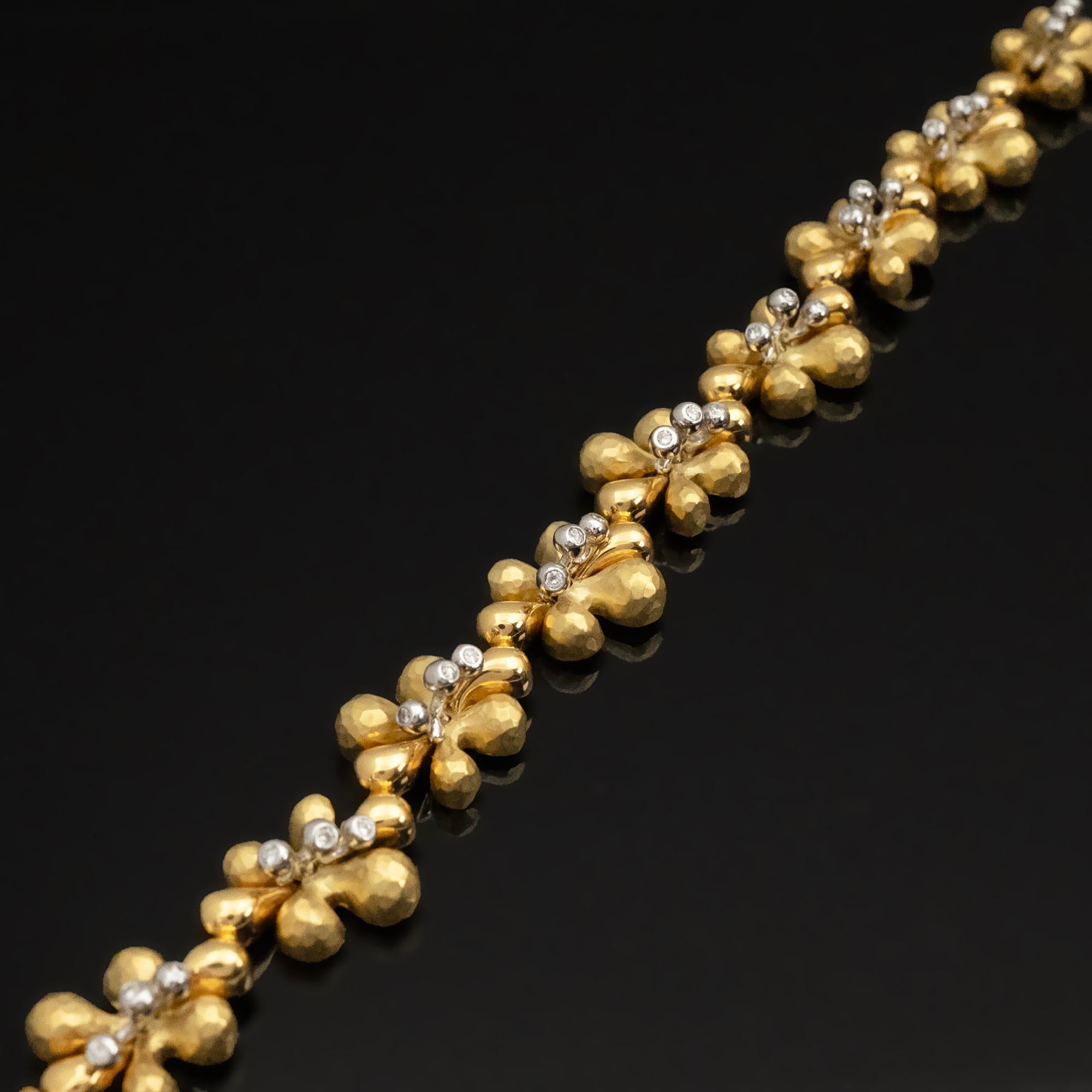 Dieses elegante Armband von Claris.A besteht aus einer kontinuierlichen Abfolge von sanft konturierten floralen Motiven aus poliertem Gold. In der Mitte jeder Blüte befinden sich drei kleine Diamanten, die ein raffiniertes Zusammenspiel von Textur,