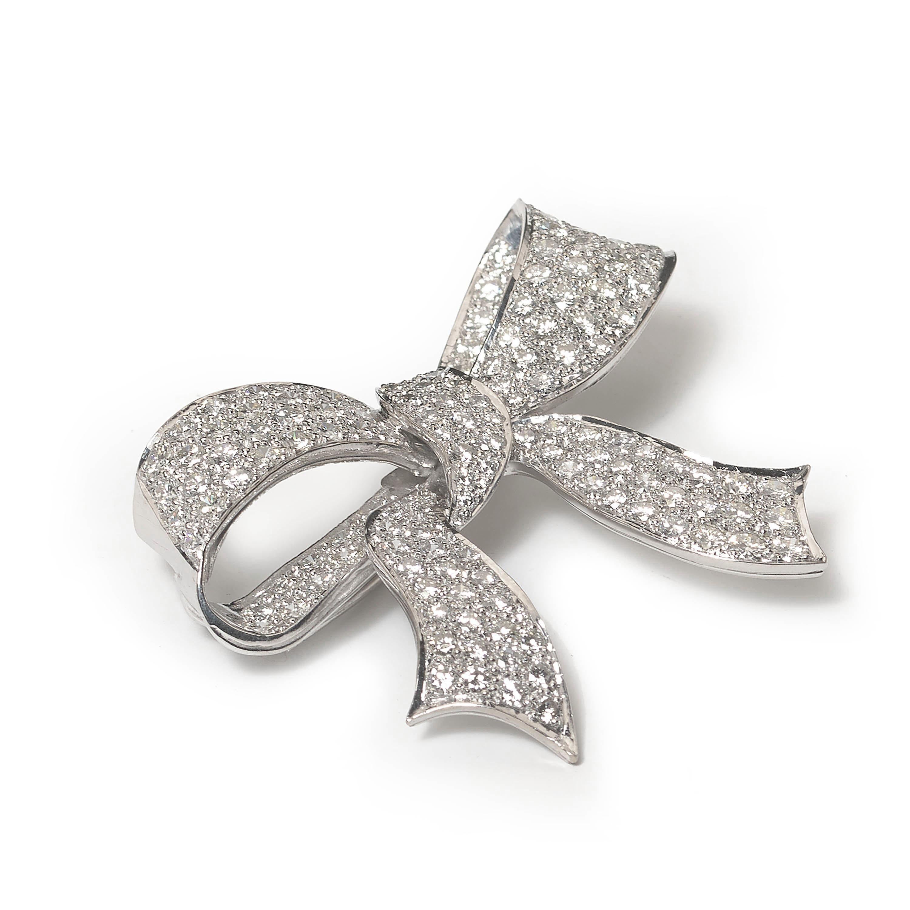 A late 20th century diamond, modern, and 18ct white gold bow brooch, with approximately 15.00 carats of round brilliant cut diamonds, in our opinion the colour is G to H and our opinion of the clarity is VS, in pavé settings, hallmarked for 18ct