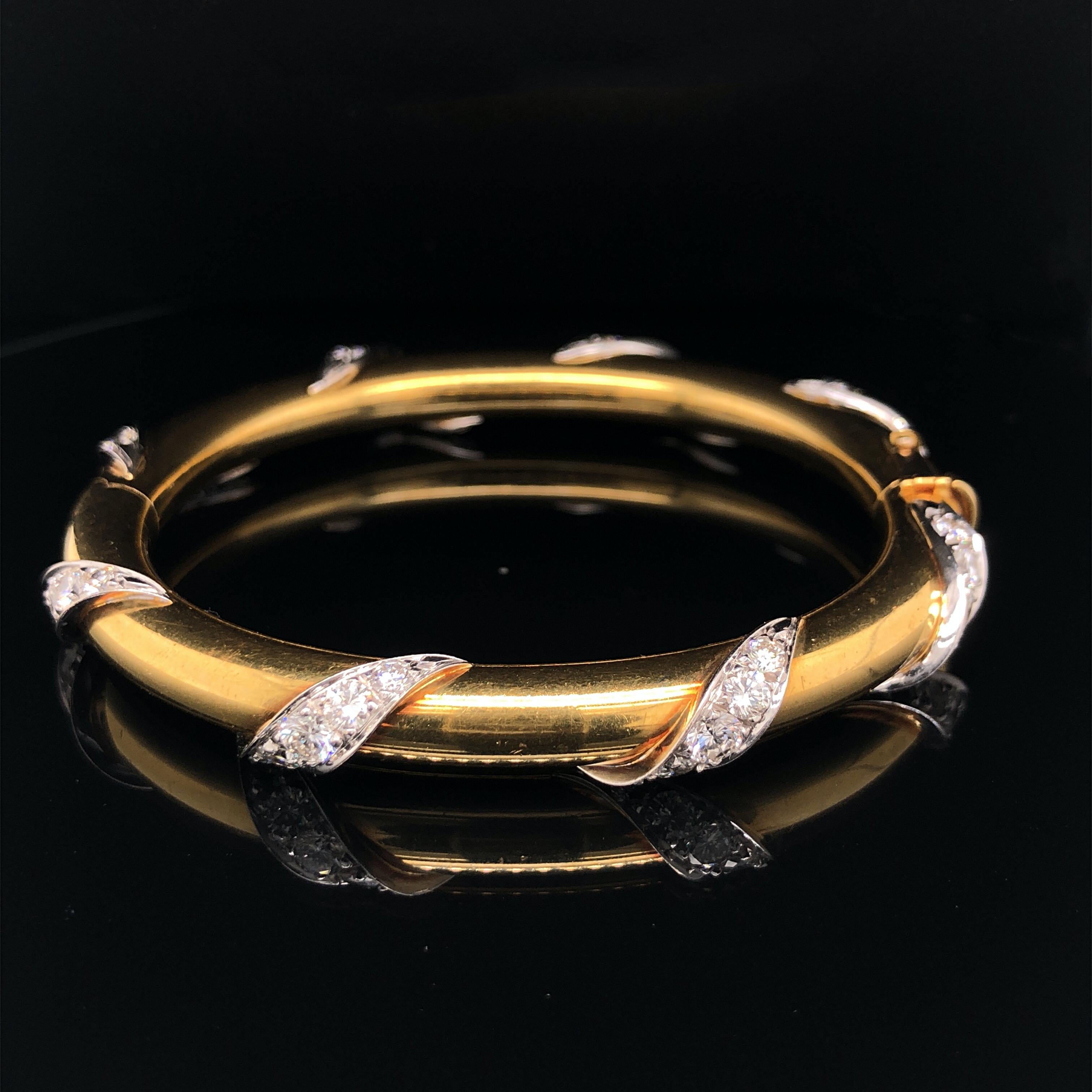 A diamond and 18k yellow gold bangle, 20th Century. 

The bangle is oval shaped with an inner diameter of 5.8cm wide. It is designed with 8 engulfing panels, which are set with round brilliant cut diamonds. The total diamond weight is approximately