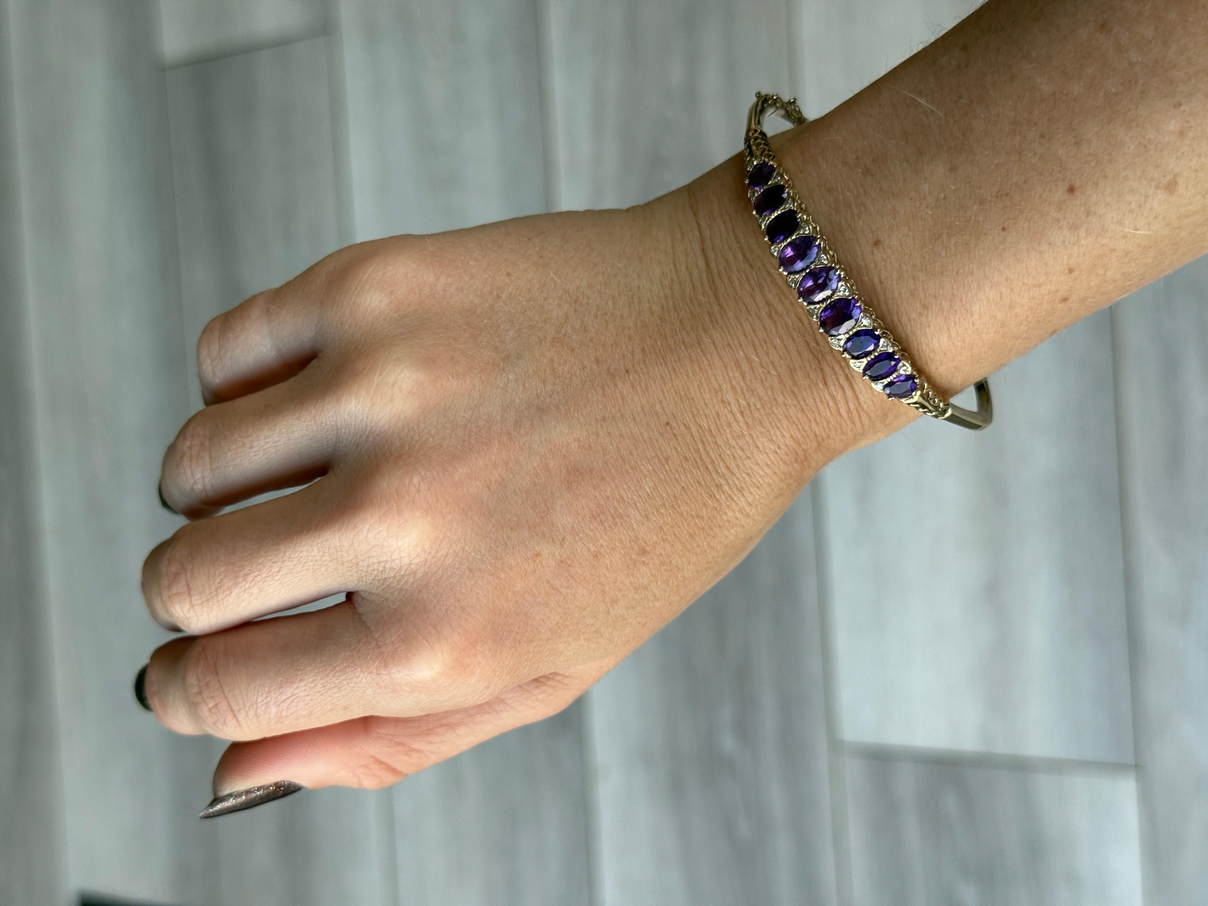 An exquisite bangle. Set with nine Amethyst stones which total 4.4ct. In between all of these gorgeous stones are pairs of diamond points, each diamond measures 1pt. All modelled in 9 carat yellow gold.

Diameter: 6cm (from hinge to clasp)
Inner