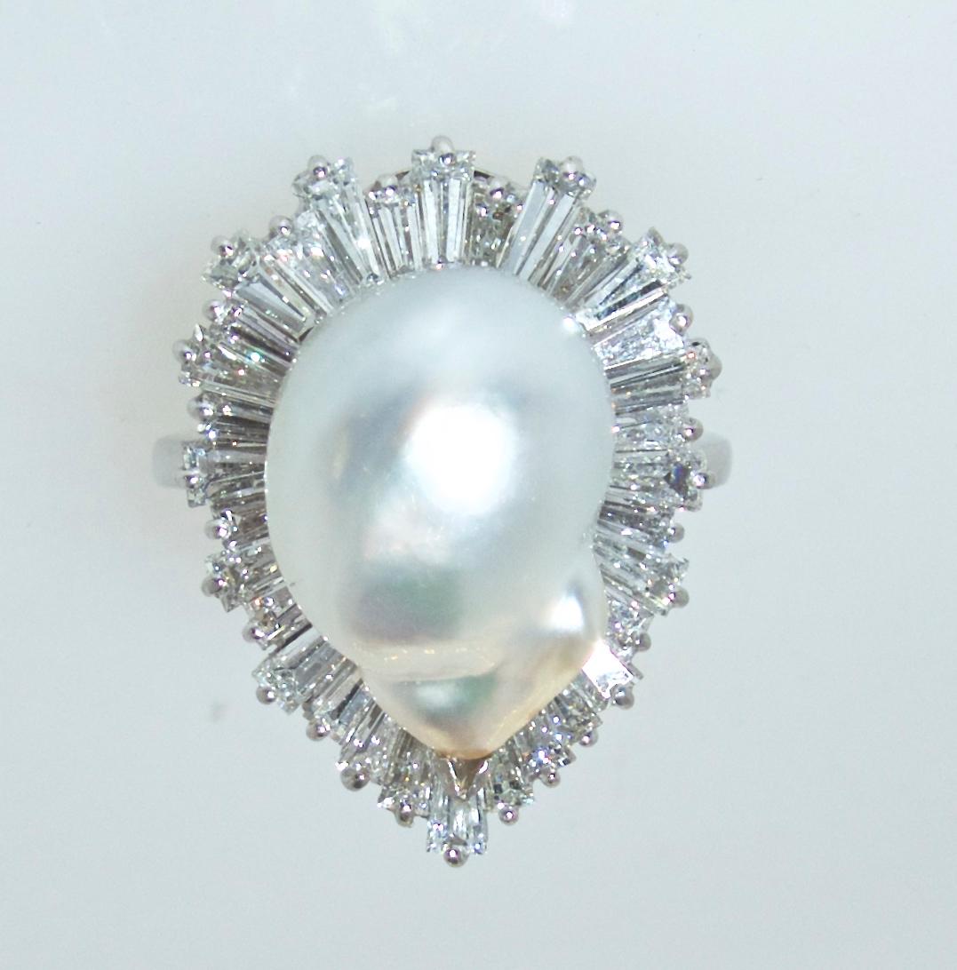 34 fine white well matched tapered baguette cut diamonds estimated to weigh approximately 2.0 cts., they are near colorless, H) and very slightly included, (VS1).   These diamonds, prong set, surround a natural white fine Baroque (free-form) pearl