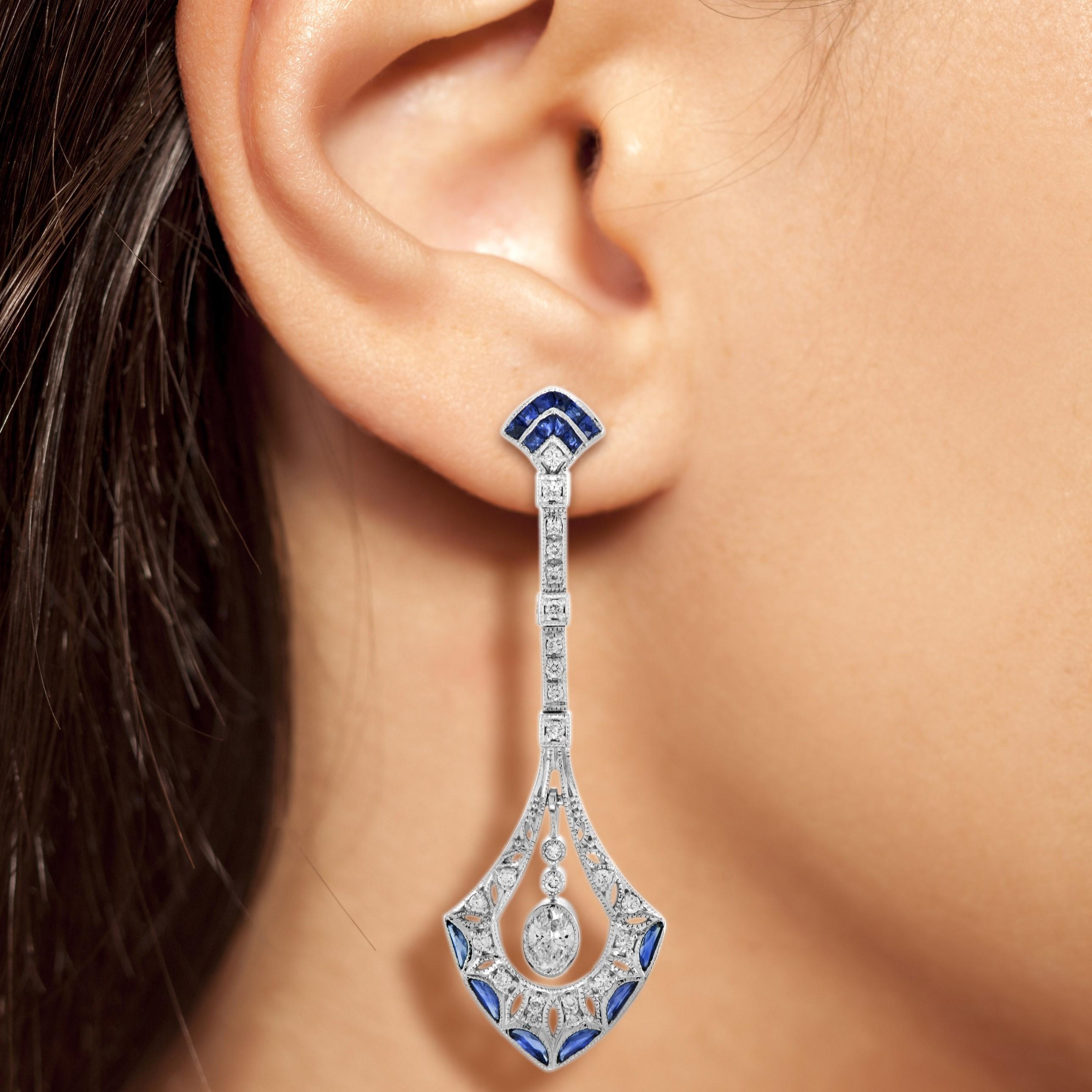 These Art Deco inspired drop earrings features approx. 0.76 carats of total diamonds and approx. 0.97 blue sapphires finished in a dazzling 18k white gold setting. Both glamorous and imaginative, these drop earrings could be the showstopper addition