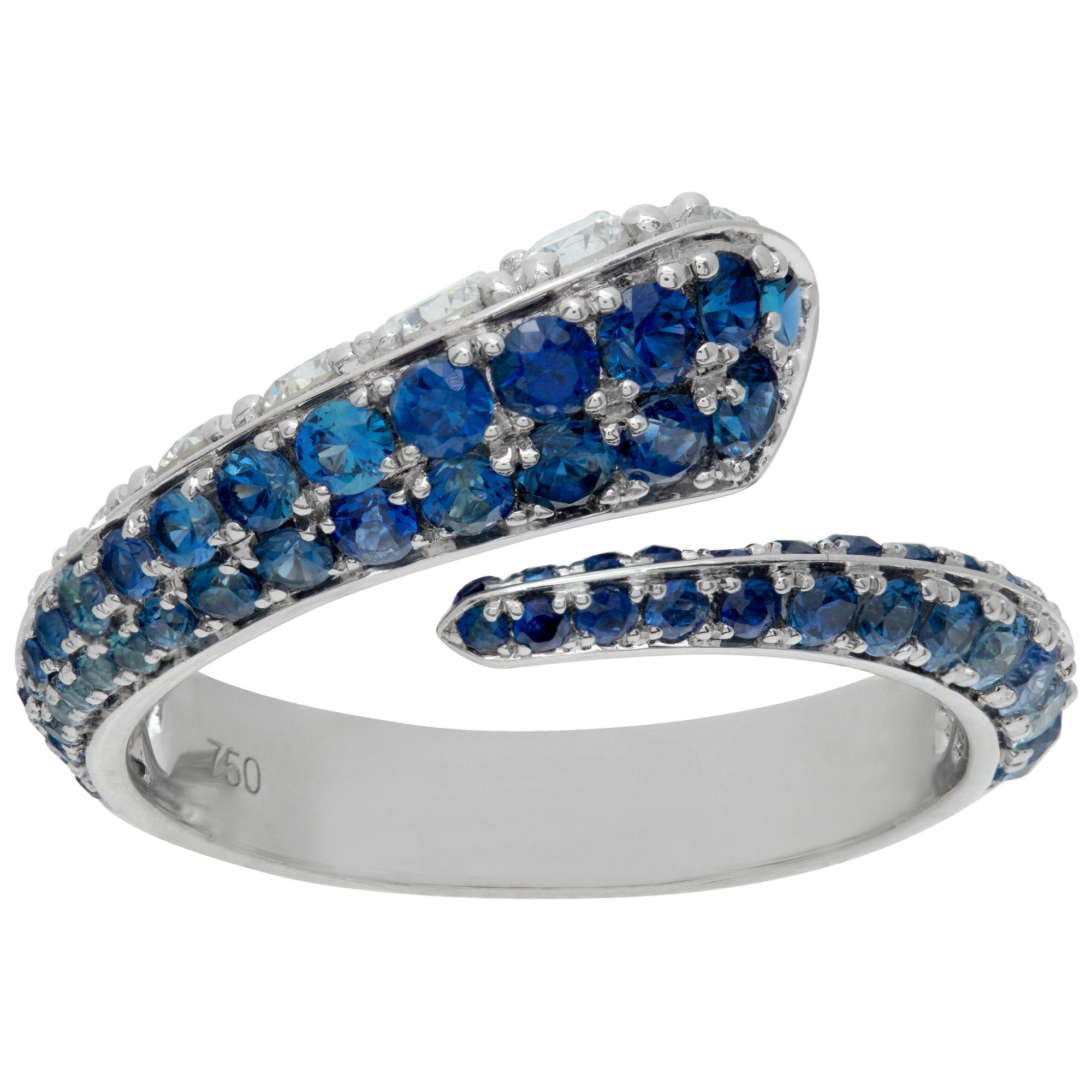 Diamond and blue sapphire crossover ring in 18k white gold. Round brilliant cut diamonds approx. weight: 0.54 carat, estimate: G-H Color, VS Clarity. Round brilliant cut blue sapphire approx. weight: 1.28 carat. . Size 6..This Diamond/Sapphires ring