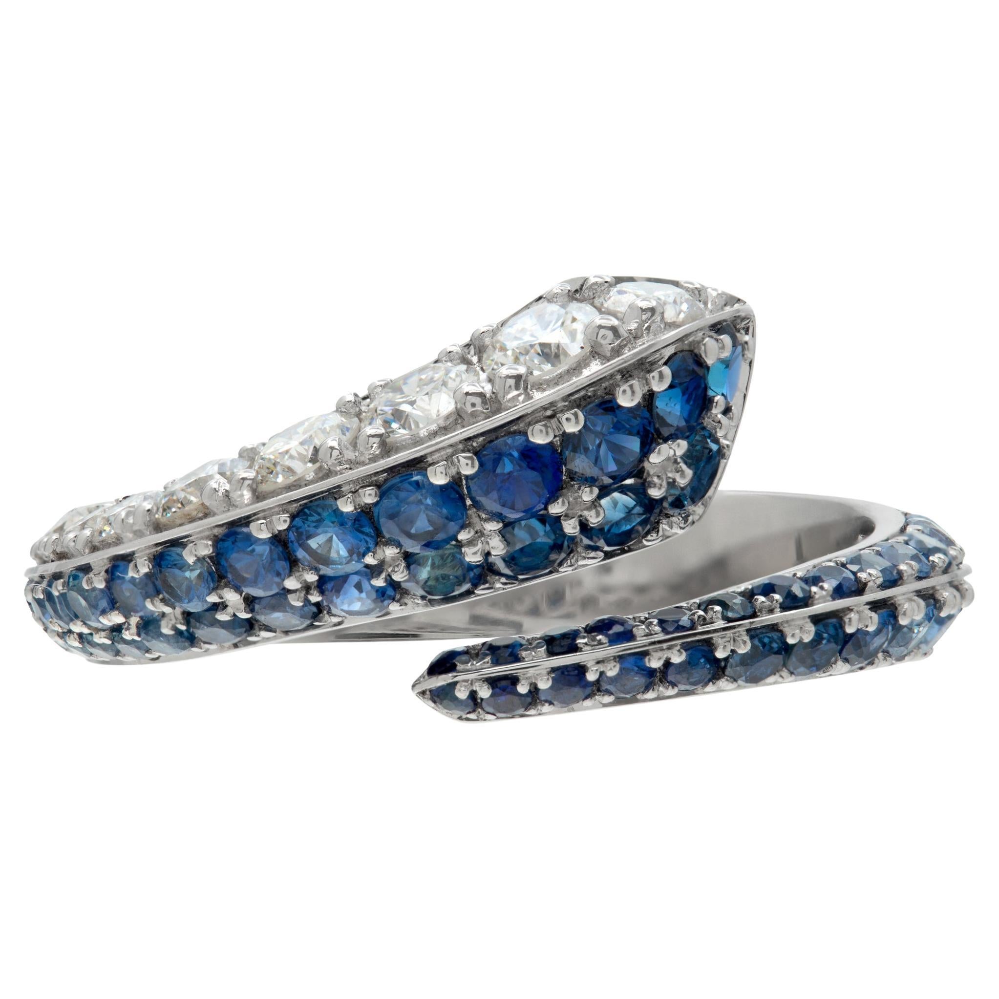 Diamond and blue sapphire crossover ring in white gold. For Sale