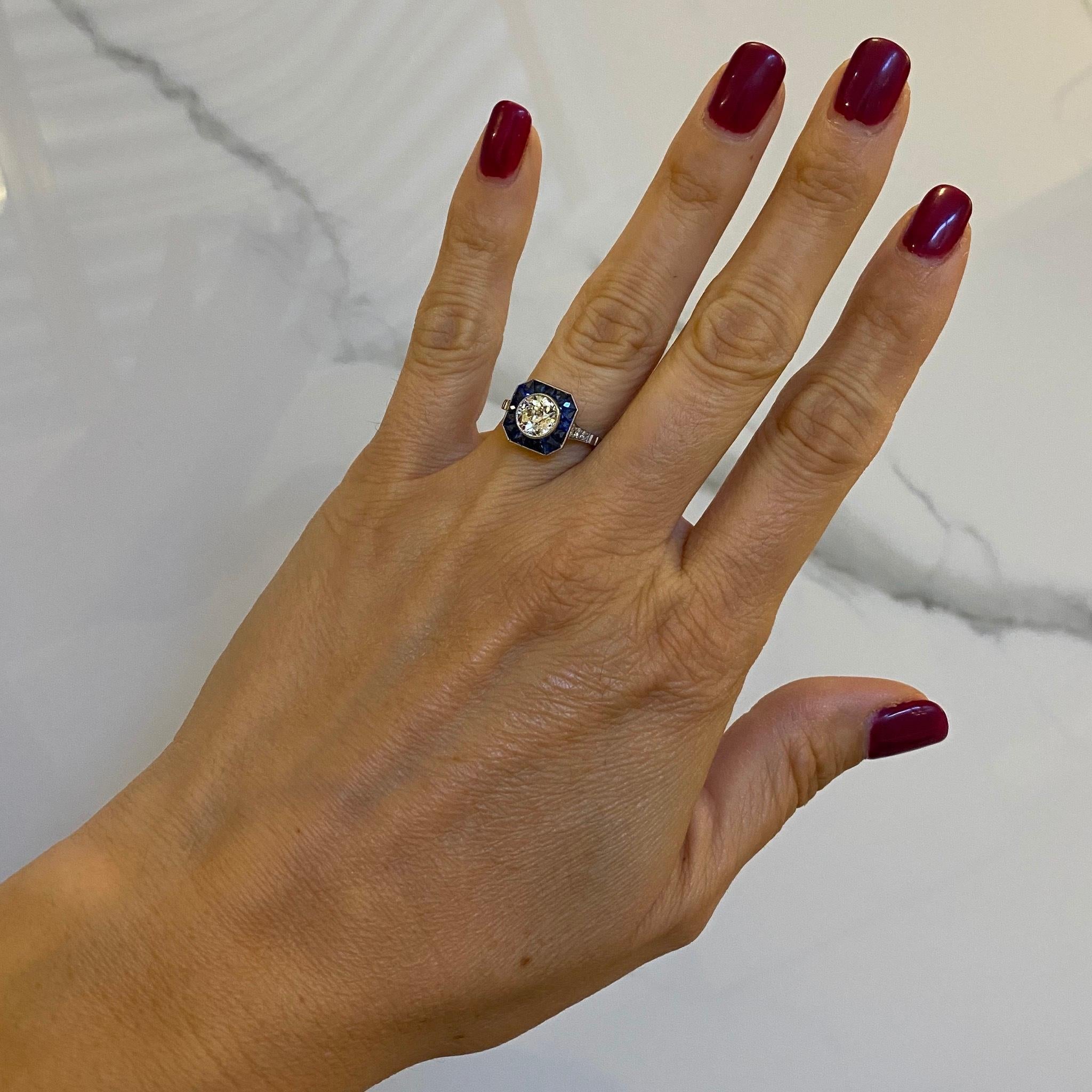 Beautiful, Timeless and finely detailed Art Deco Style Platinum Halo Ring, center securely nestled with an Old European cut Diamond, weighing approx. 1.02 Carat, H/I color, SI1 clarity; surrounded by French cut Blue Sapphires and small Diamonds