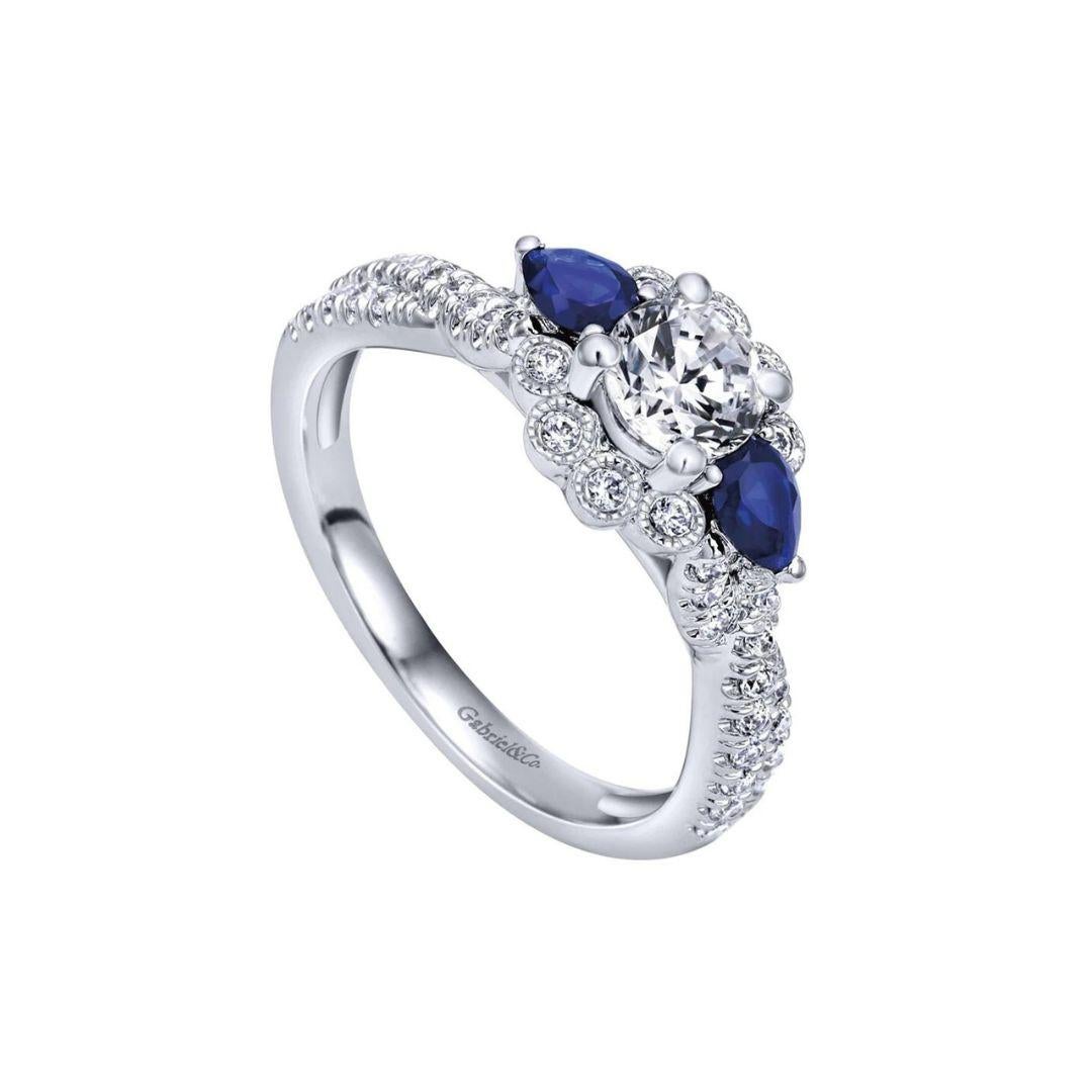 Ladies' 14k White Gold Diamond and Blue Sapphire Engagement Ring by Gabriel Co. Romantic scalloped design combined with milgrain finish give this ring a vintage Edwardian look. Center diamond is 0.30 ct weight, H color, SI1 clarity. Side diamonds