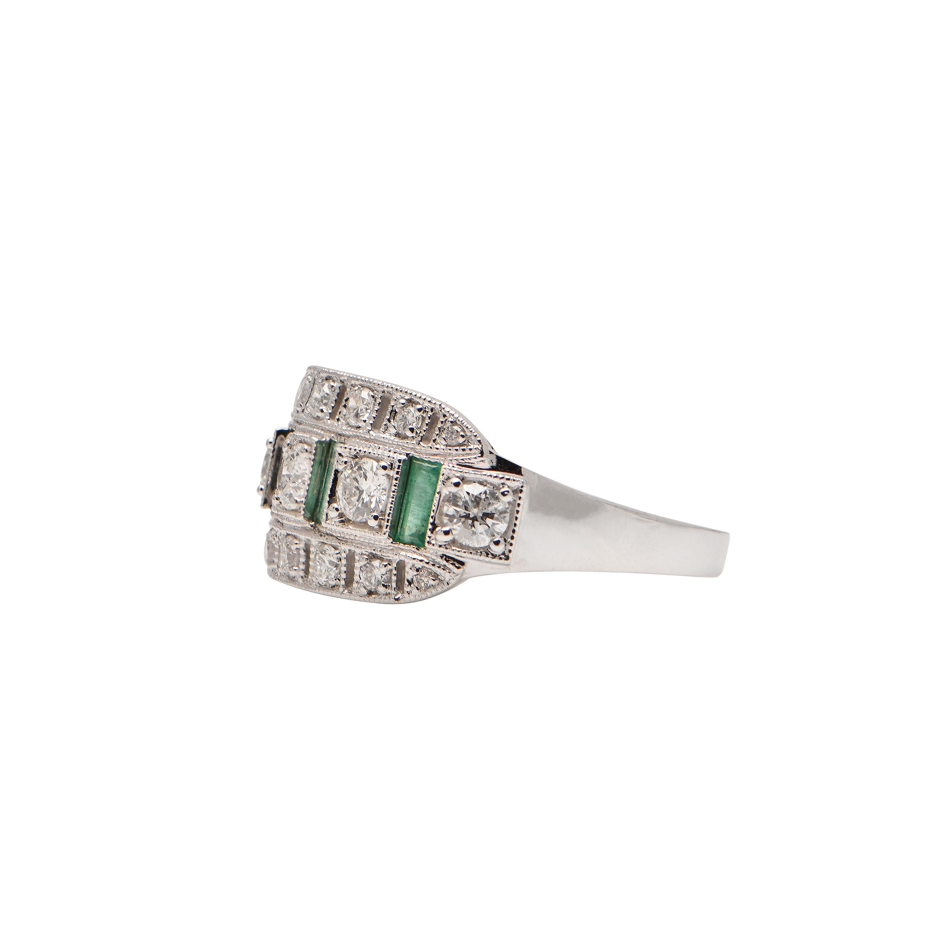 An 18ct White Gold Art Deco Dress Ring showcasing 4 Emeralds totalling 0.36ct, 5 Diamonds totalling 0.60ct, and 14 Diamonds totalling 0.27ct. Size M.
