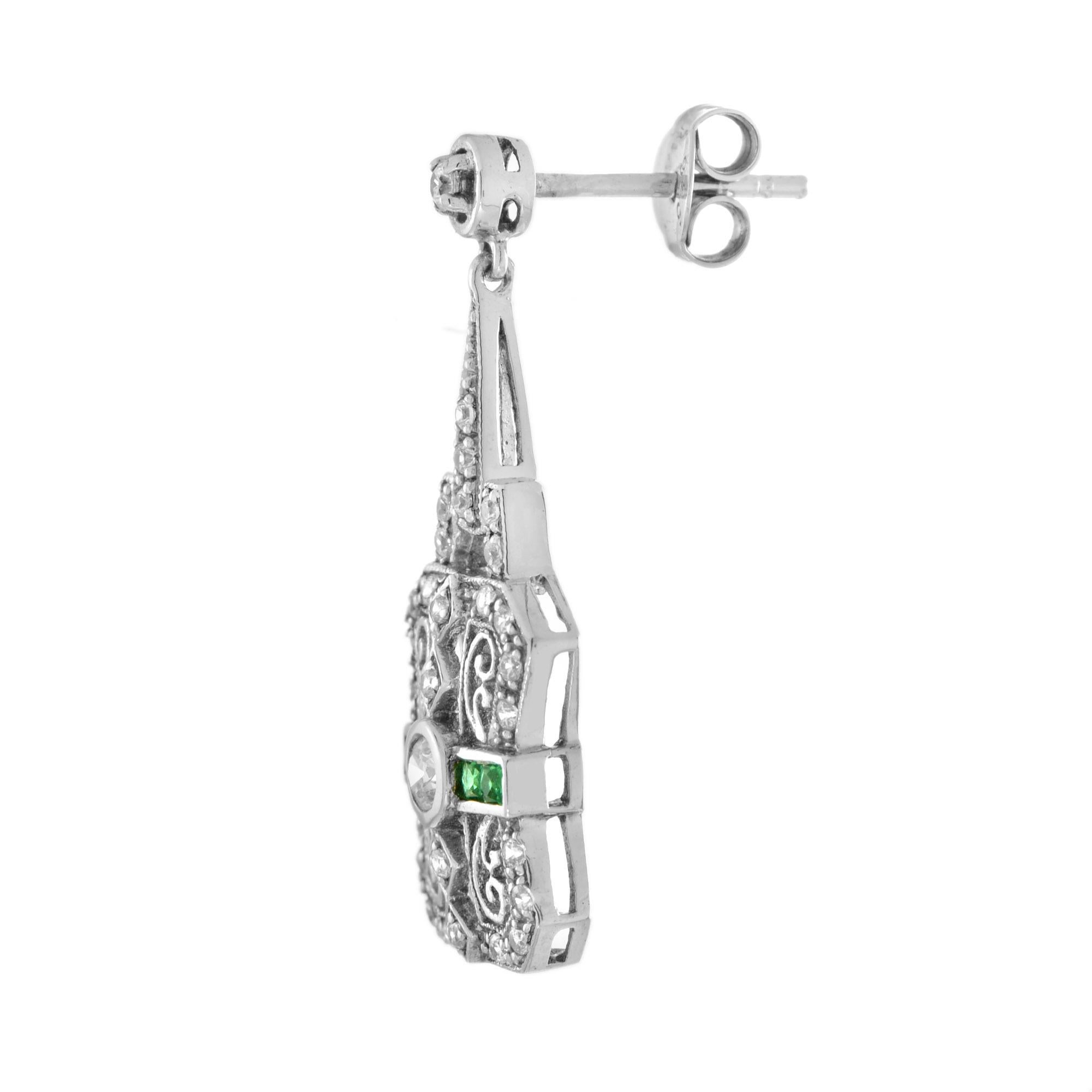 An Art Deco-inspired diamond and emerald white gold filigree drop earrings. Featuring one round brilliant cut diamond of approximately 0.17 carat each, graded H color, SI clarity. Accented by 4 French-cut emeralds and 31 round-cut diamonds on each