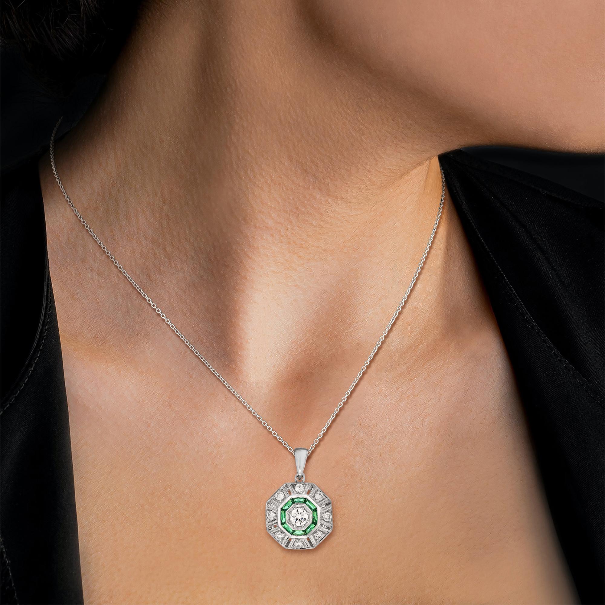 An 14k white gold Art-Deco design diamond and emerald target pendant, center diamond with an outer of round diamonds an inner one of French cut emeralds and finished with millgrain edging.

Information
Metal: 14K White Gold
Width: 15 mm.
Length: 22