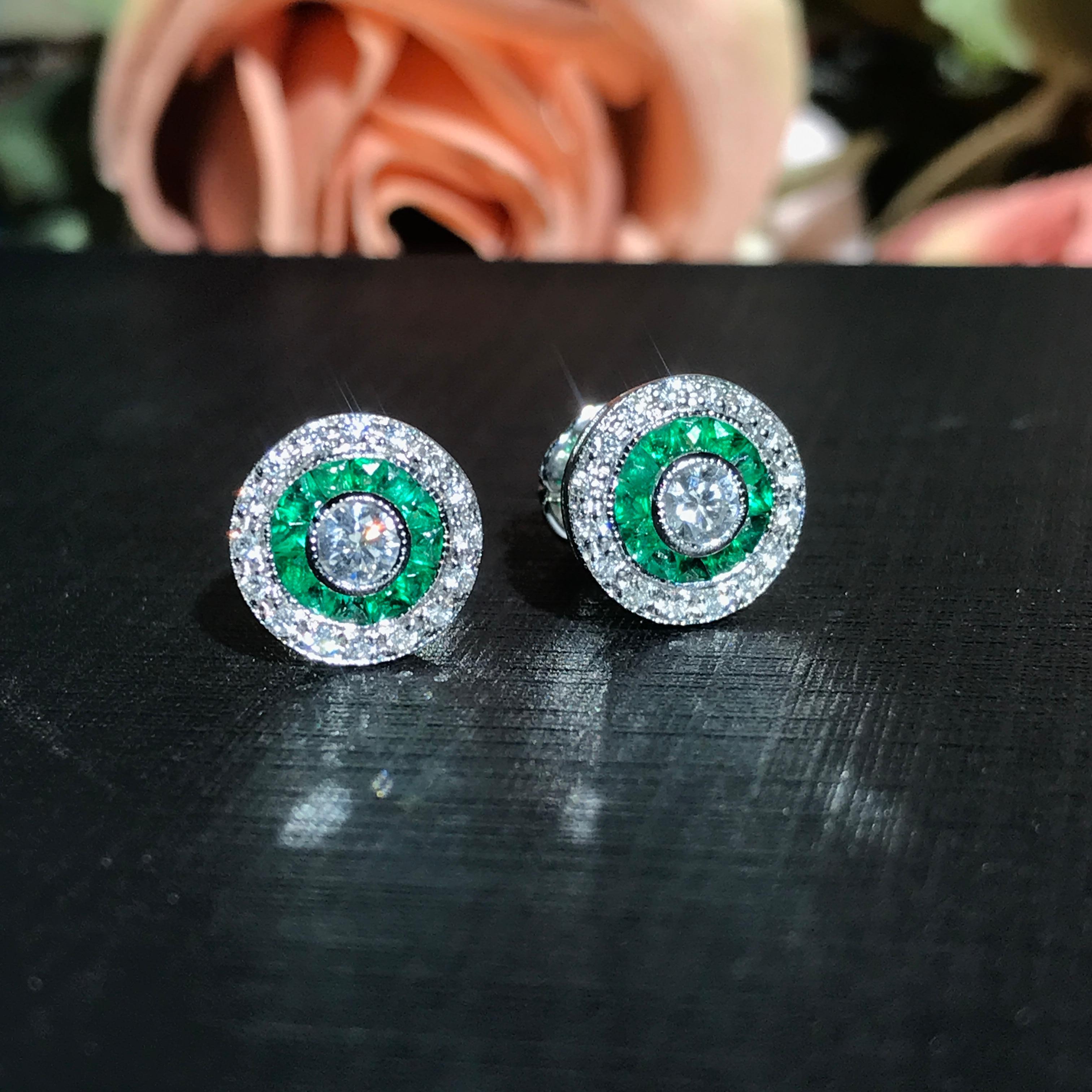 Gli orecchini Target con diamante tondo brillante e smeraldo in stile Art Deco presentano un diamante tondo brillante di 3 mm al centro, circondato da smeraldi vibranti. Gli smeraldi sono elegantemente incorniciati da diamanti che esaltano la