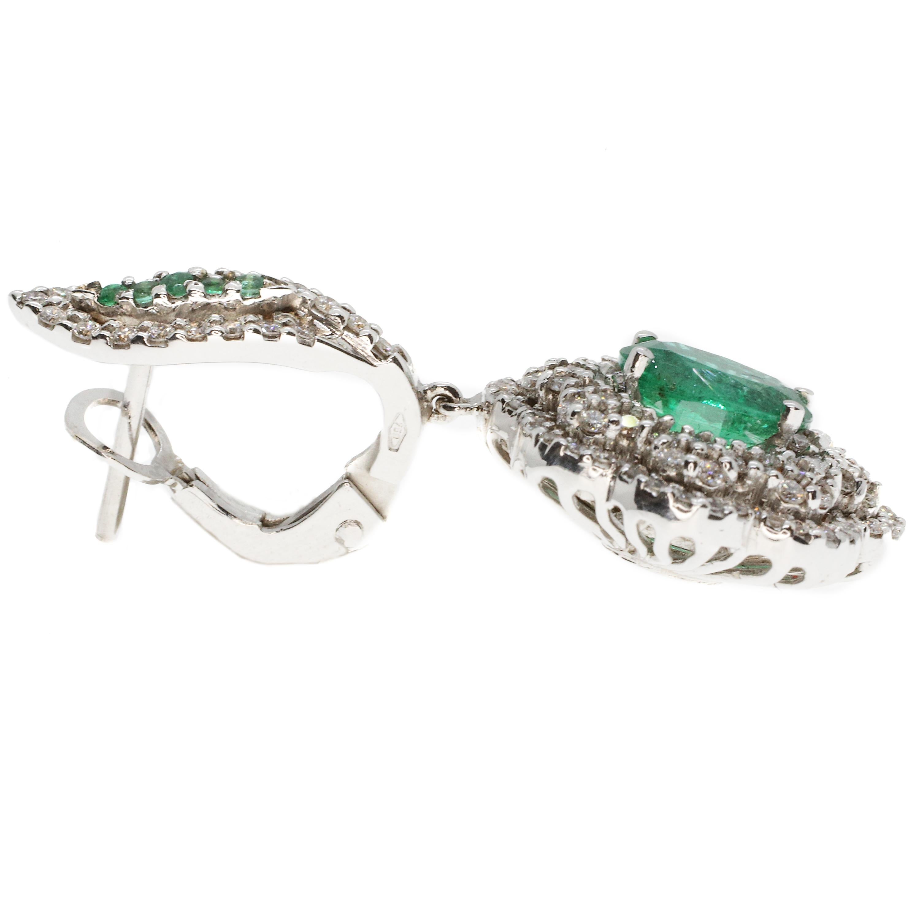 These drop earrings, masterfully created by hand from 18-karat white gold are each set with a vibrant emerald. Clusters of brilliant white diamonds 