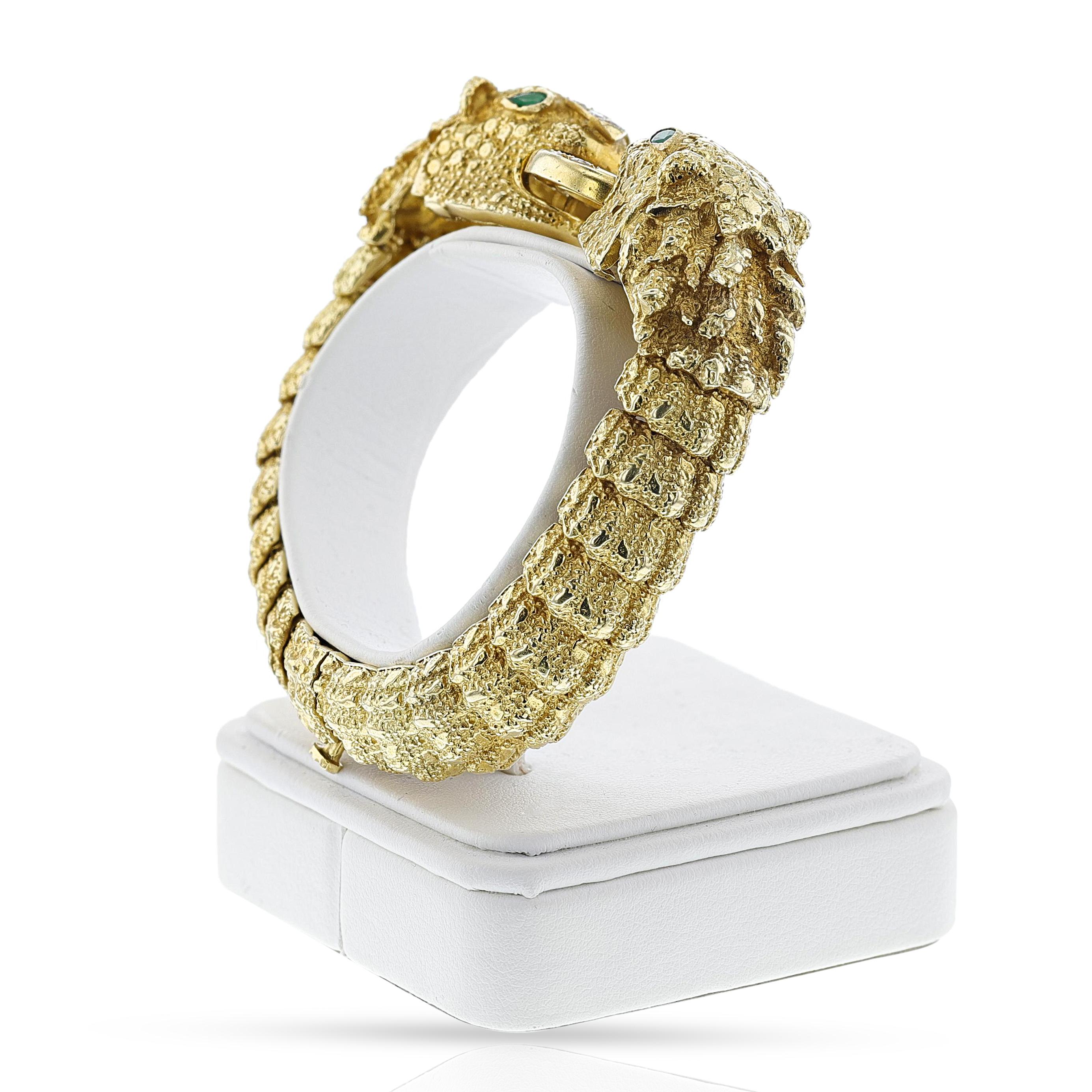 A Diamond and Emerald Lion Cuff Bangle made in 18k Yellow Gold. The bangle weighs 97.84 grams. The length is 6.25 inches. 