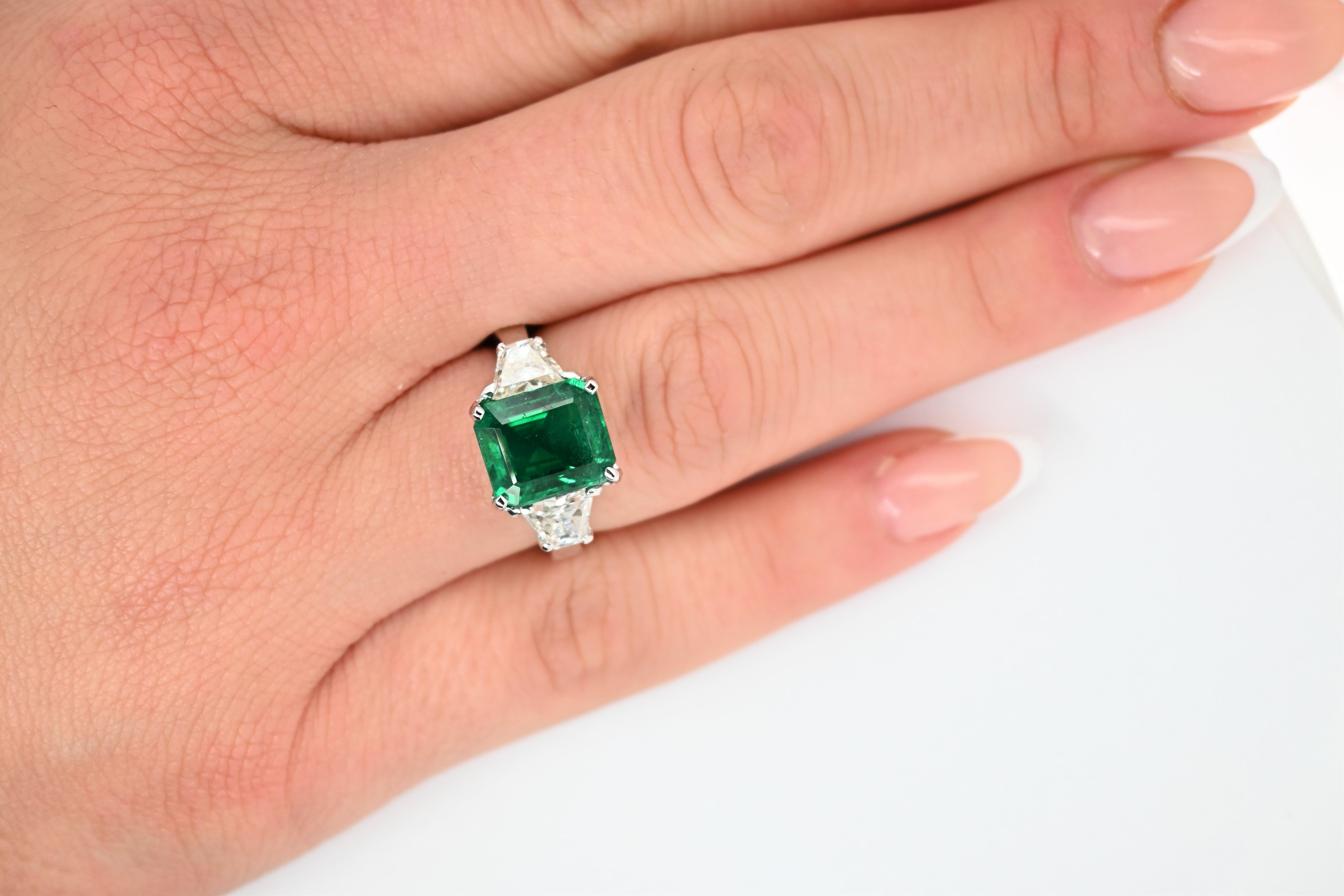Original Magnum Creations Ring, features 0.95 carats of two white diamonds on the sides, and 4.05 carats of emerald as a center stone, mounted on a platinum casting.

This ring is impressive, the deepness of the center emerald and the shine of the