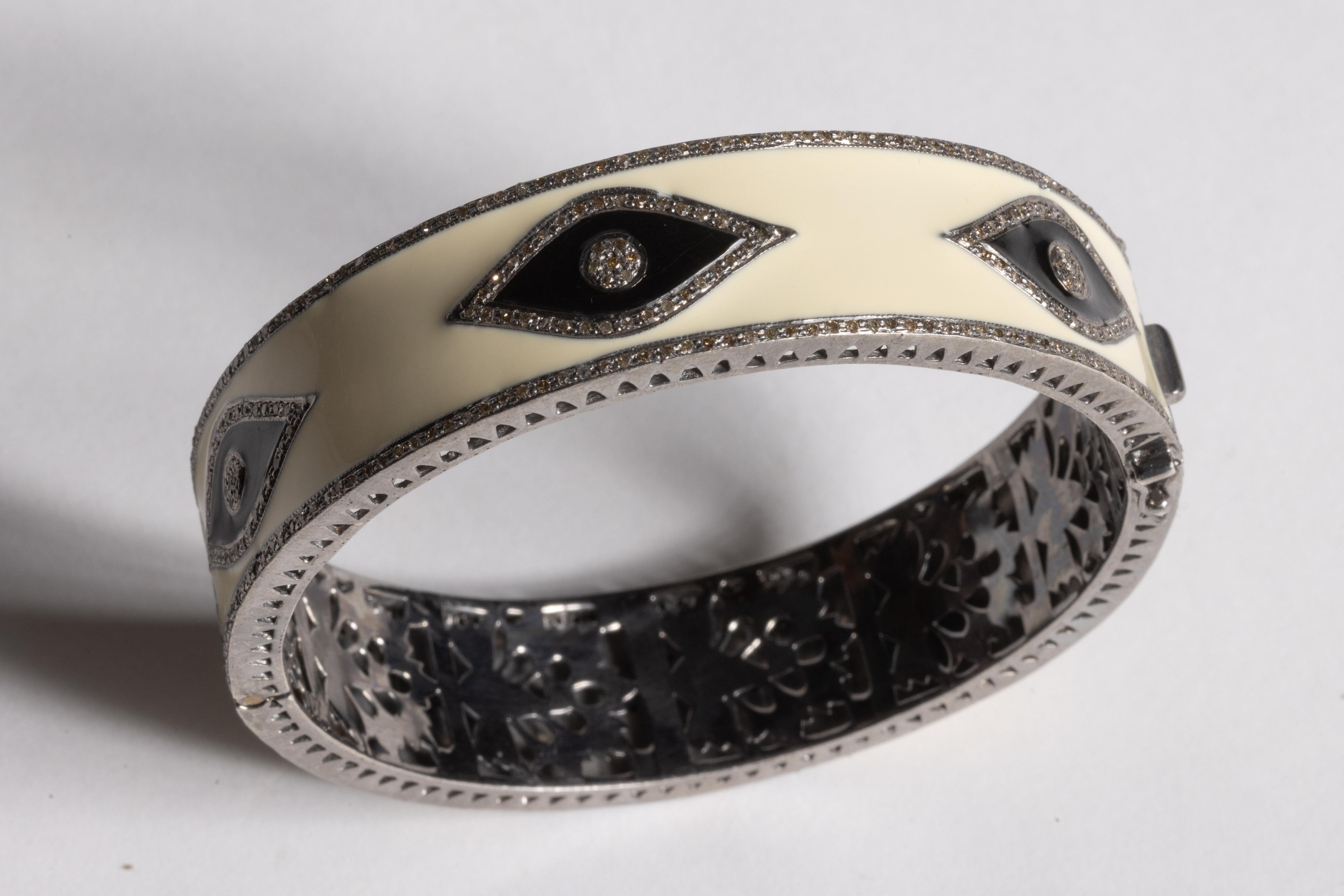 Vous offrant toute la protection contre le mal, ce bracelet bangle en émail blanc présente six motifs d'œil maléfique en émail noir avec des diamants soulignant les yeux et des diamants comprenant les yeux.  Les mêmes diamants ronds de taille