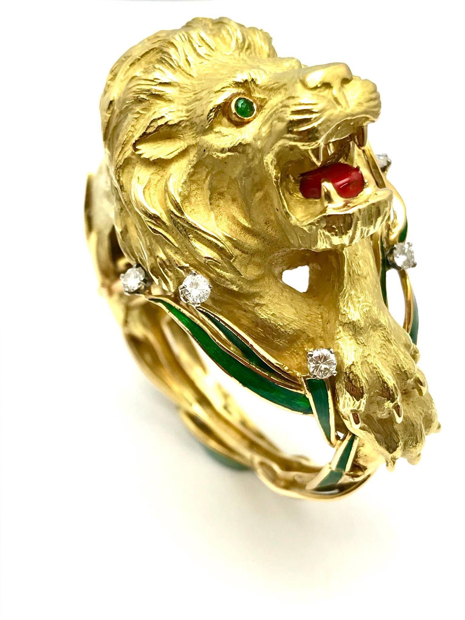 A round brilliant diamond and green and red enamel 18 karat yellow gold lion bangle bracelet.  The bracelet is designed as the lion sitting in the in the green enameled grass, letting out a mighty roar, exposing his red enameled tongue.  The lion is