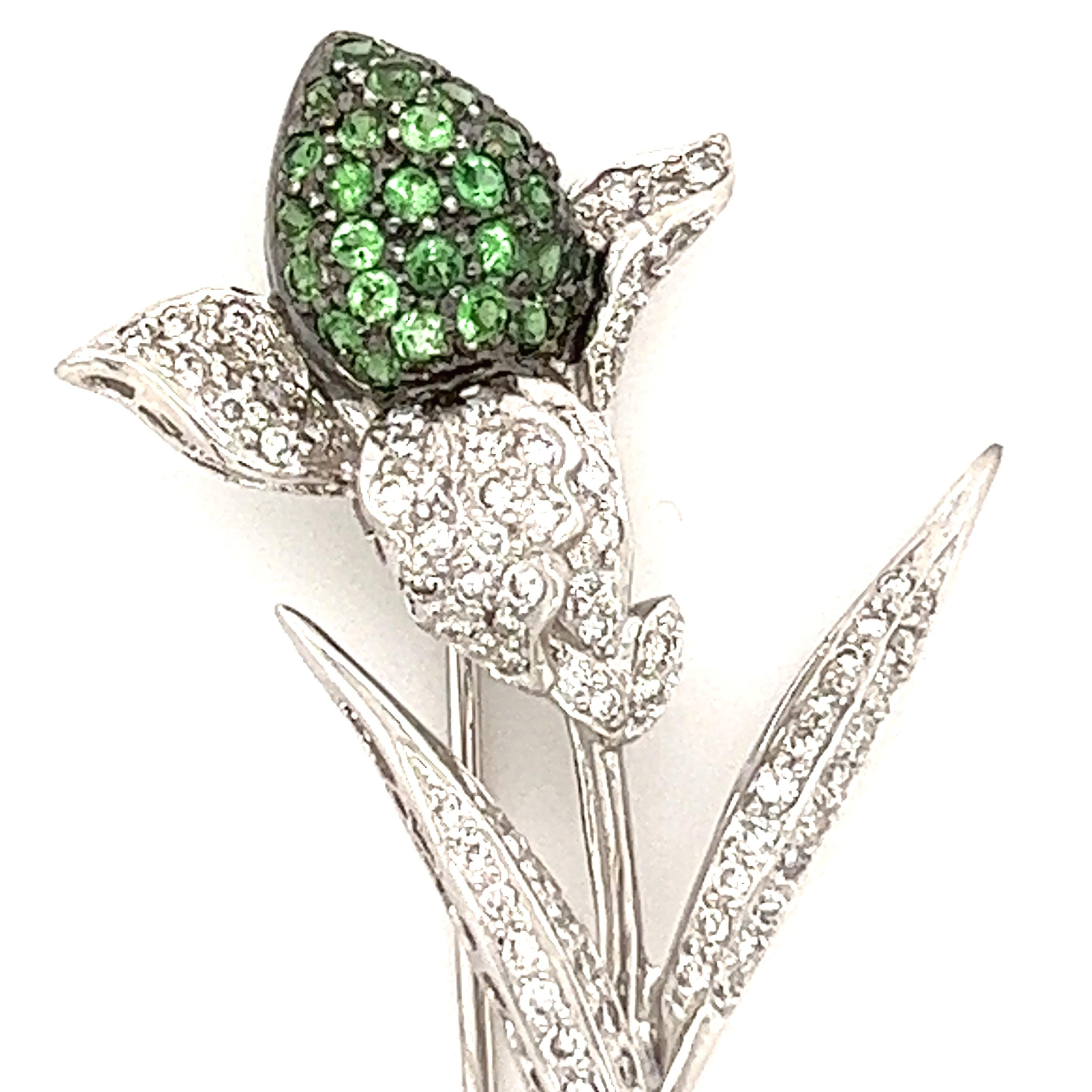 This unique pin dresses up any outfit. It has .42cts of white diamonds, G color, VS2 clarity, with .15cts of green garnets set in 18k white gold. 
