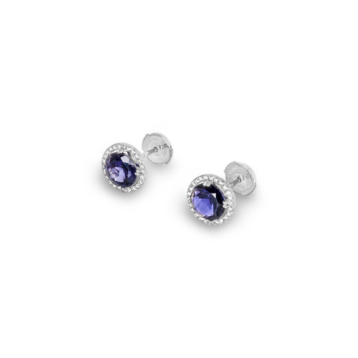 A beautiful pair of 18k white gold diamond and iolite earrings. The earrings are each set to the centre with a round brilliant cut iolite gemstone in total weighing 3.11ct with a deep blueish-purple. Complementing the central stone is a halo of 25