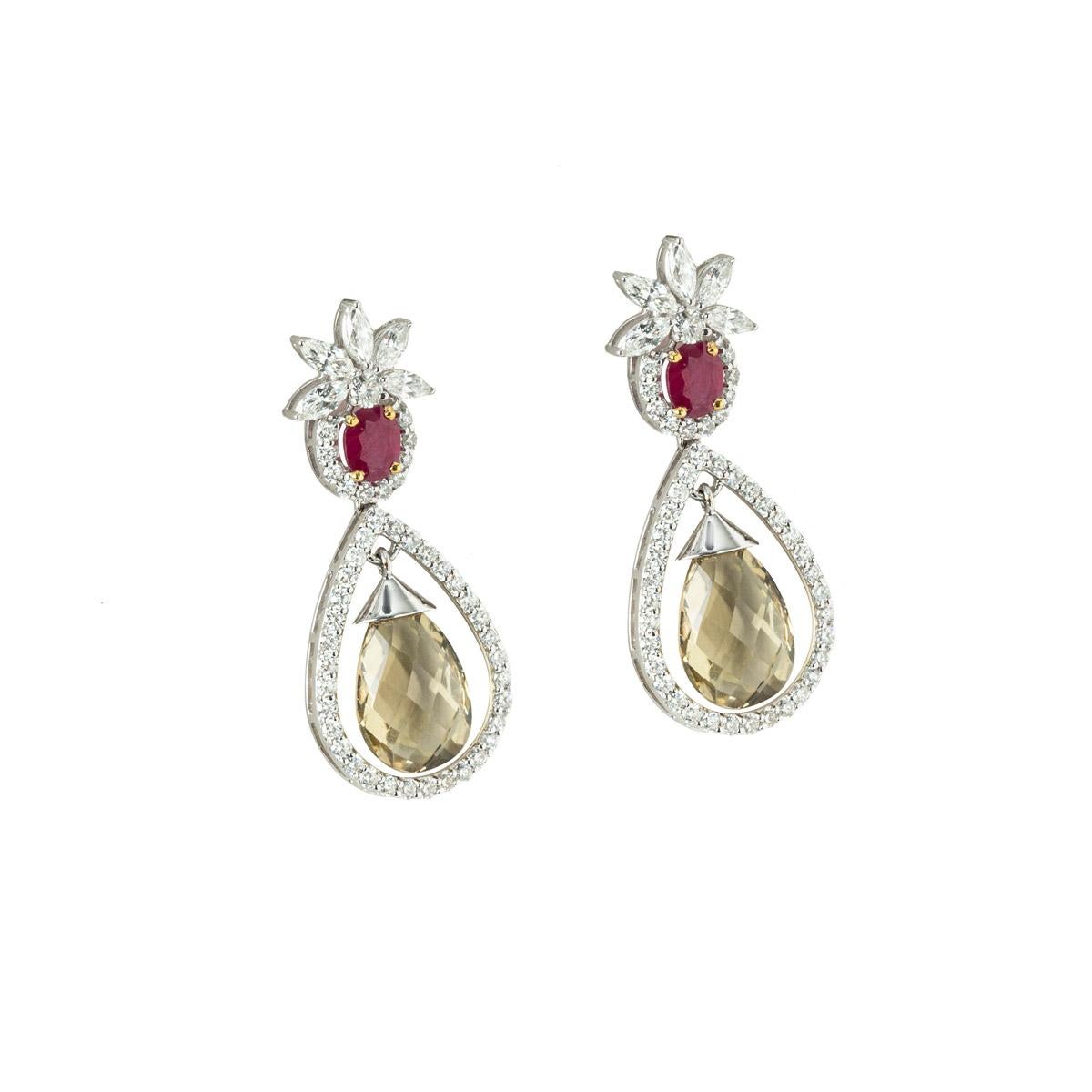 A unique pair of 14k white gold diamond and multi-gemstone drop earrings. The earrings feature ruby with half a halo of round brilliant cut diamonds under the ruby and marquise cut diamonds like a crown style above the ruby. The earrings tail off