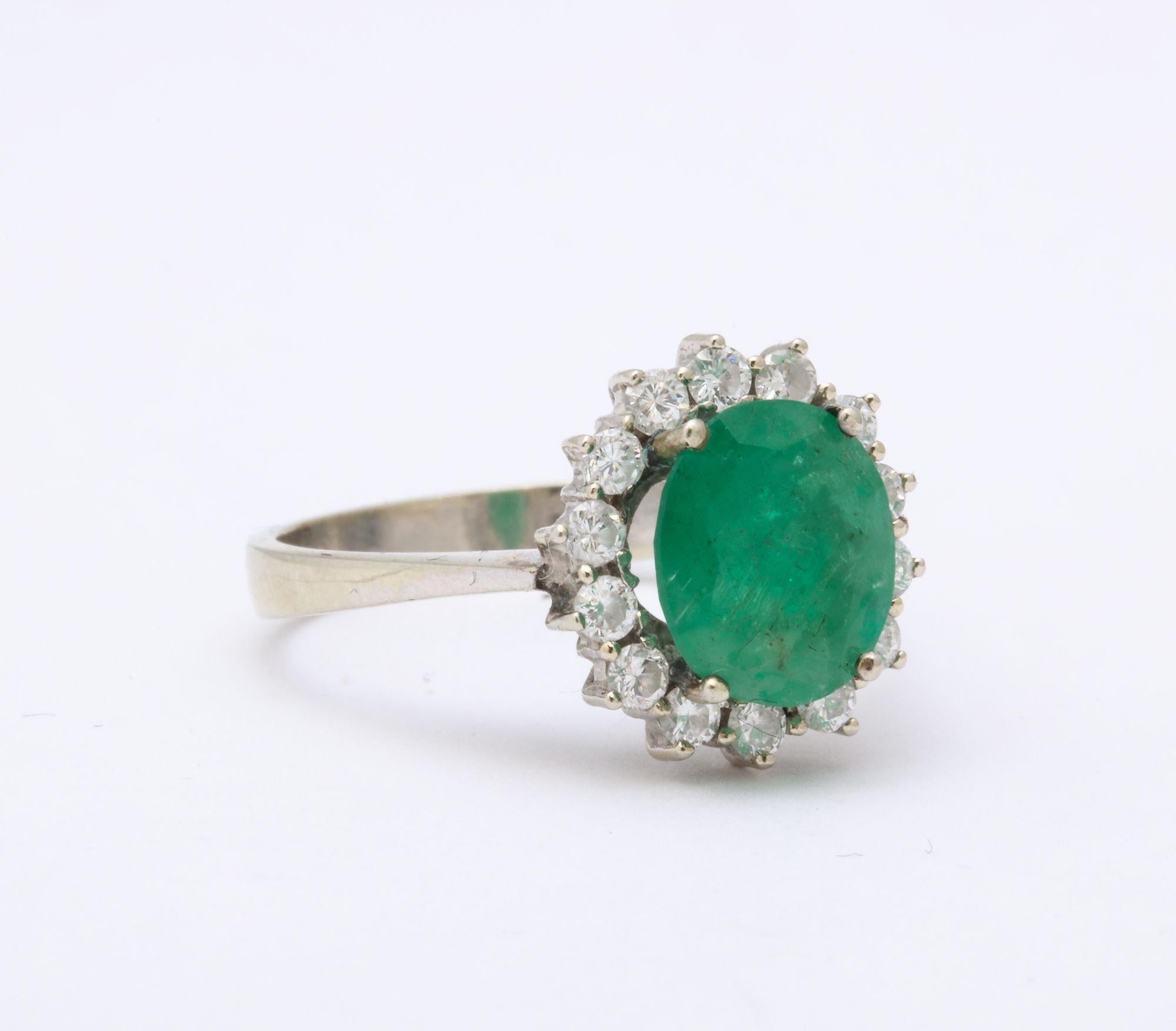 A stunning Diamond and Emerald Gold Ring. An oval mixed cut natural emerald is surrounded with round brilliant cut diamonds.