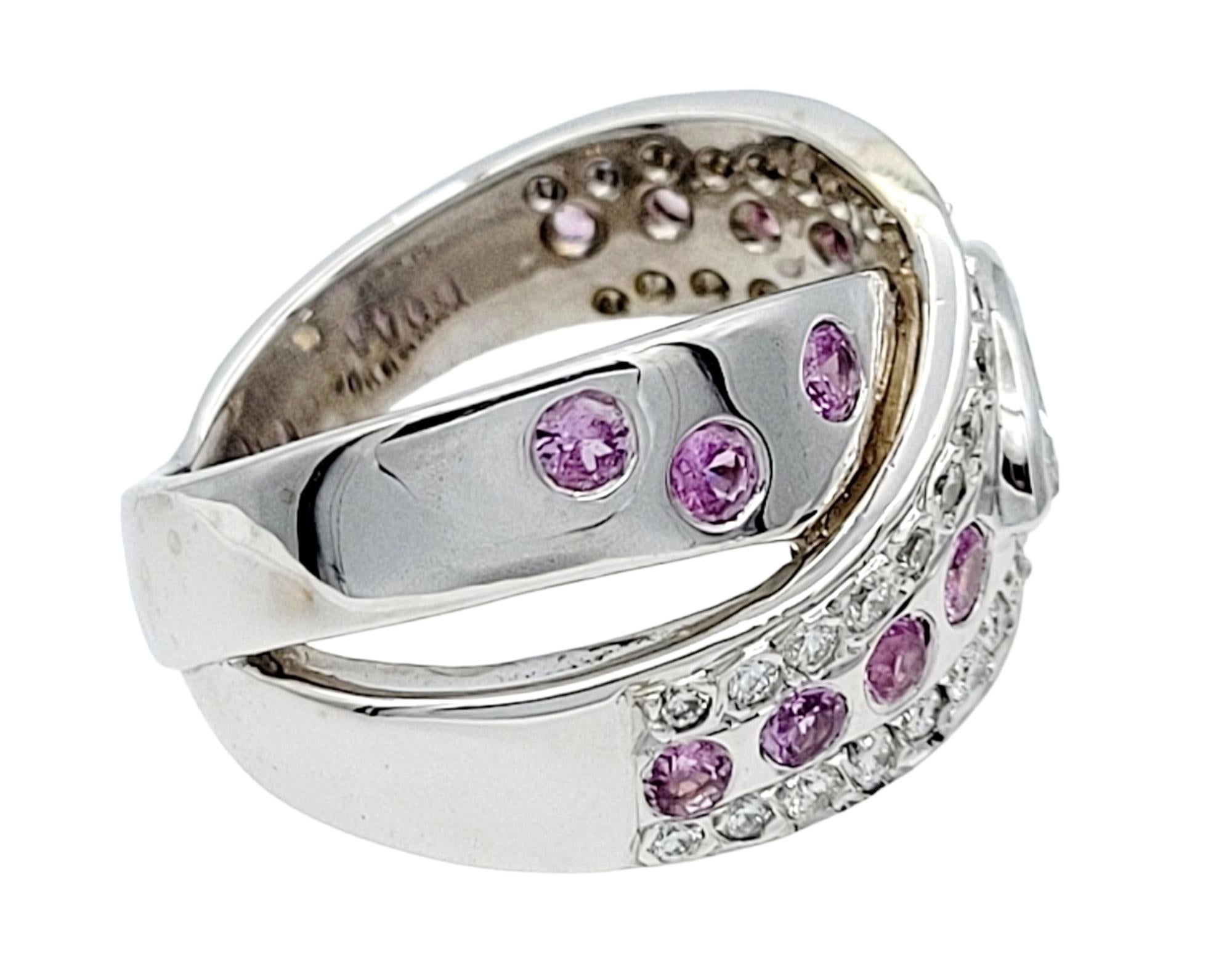 Ring Size: 7.5

This stunning 14 karat white gold crossover ring showcases a mesmerizing blend of diamonds and natural pink sapphires. The captivating centerpiece features a 0.47-carat marquise cut diamond, boasting a sparkling G color and SI-2