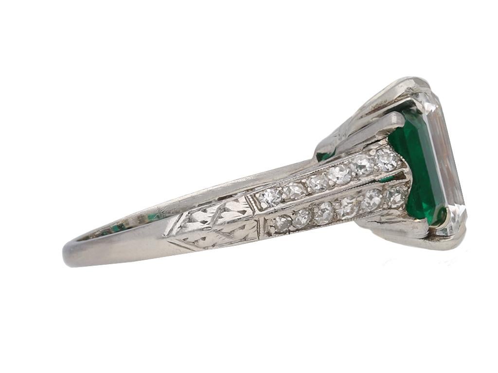 Diamond and emerald three stone ring. An emerald-cut diamond, G colour, SI1 clarity, is set to centre in an open back corner claw setting with a weight of 2.66 carats, flanked by two emerald-cut unenhanced emeralds in open back corner claw settings