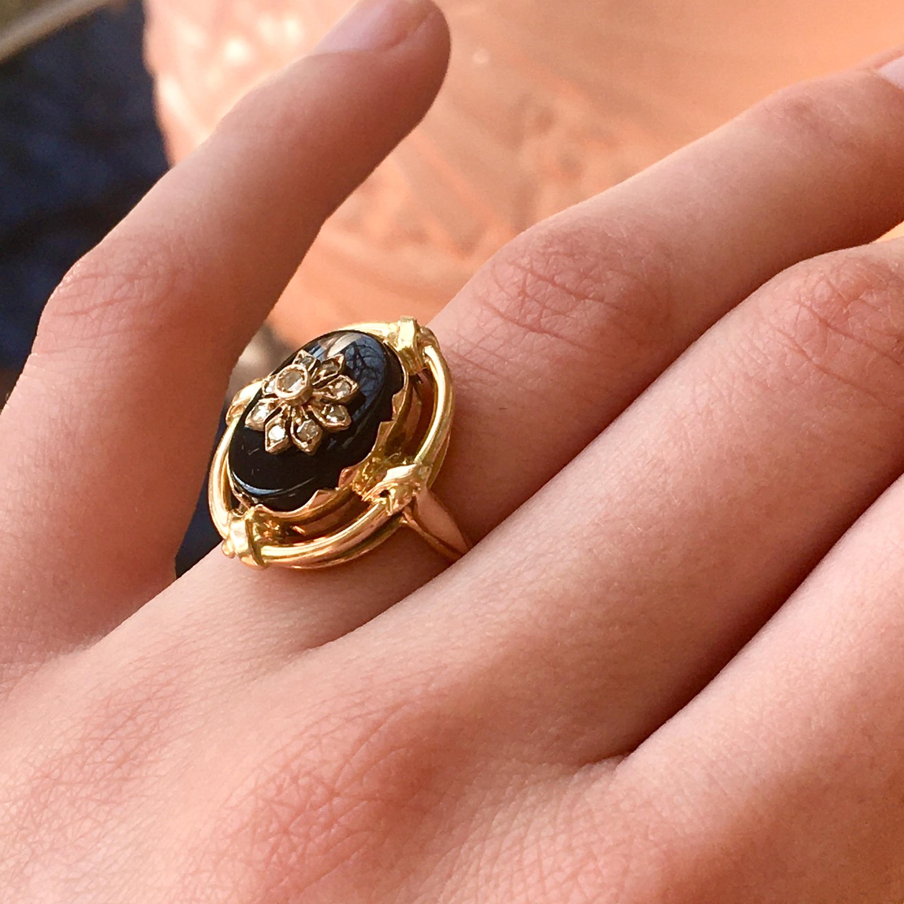 A vintage 14 karat yellow gold black onyx and rose cut diamond ring. The band of the ring is created in 14 karat gold with gold crossed figures on four sides of the frame border. The oval-shaped deep black onyx is beautifully set with a yellow gold