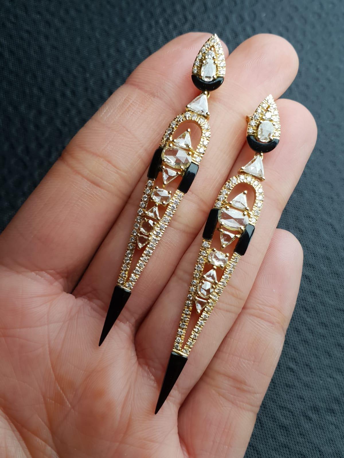 An absolutely gorgeous art-deco looking, modern pair of earrings. Various shapes of rose cut and full cut white diamonds are set in 18K Gold. The use of black onyx makes the design of the earrings very unique. This super light weight pair comes with