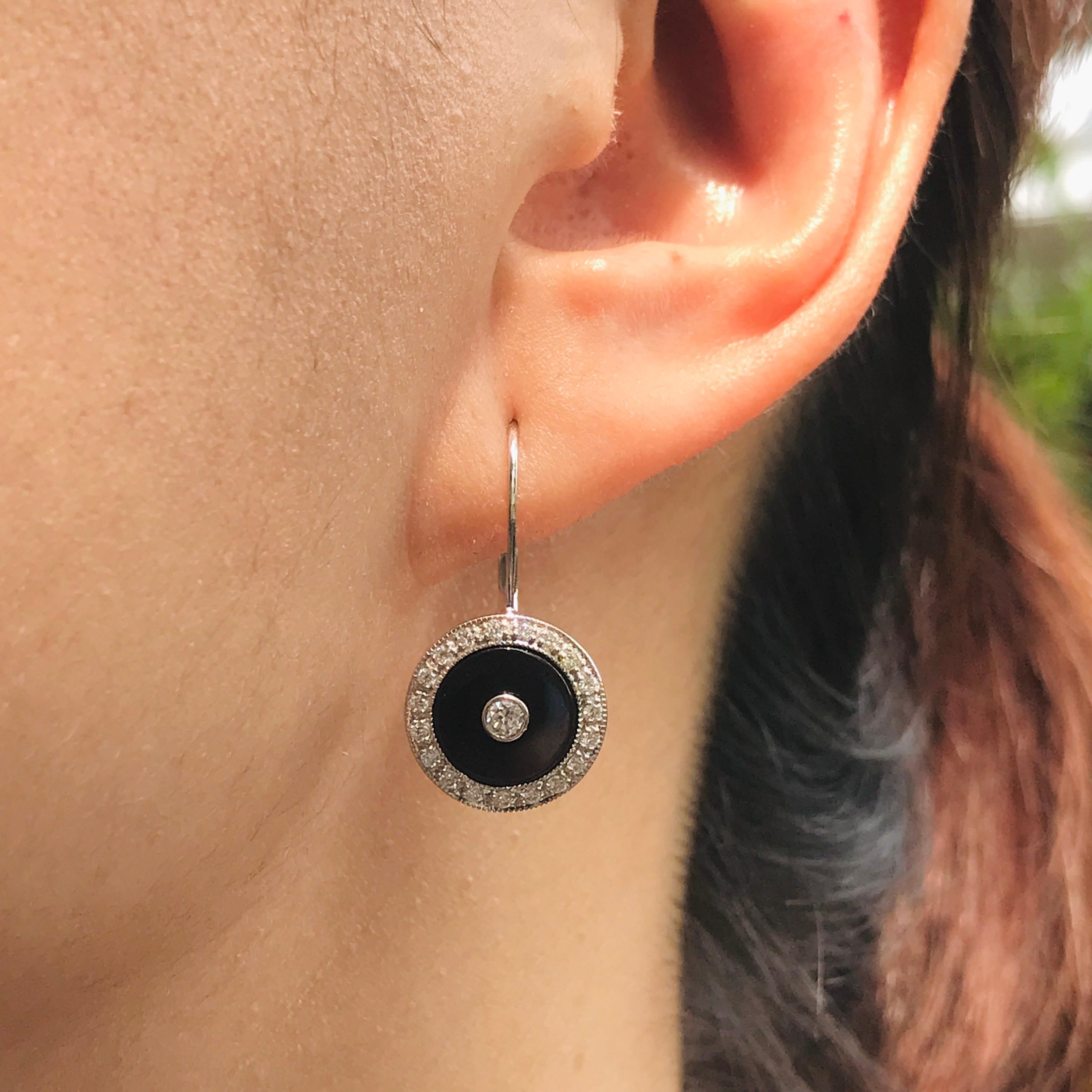 Au centre, un diamant rond brillant capte la lumière, entouré d'onyx noir épuré et encadré d'un diamant étincelant. Les lignes géométriques et les détails angulaires du style Art Deco renforcent l'allure vintage des boucles d'oreilles et en font une